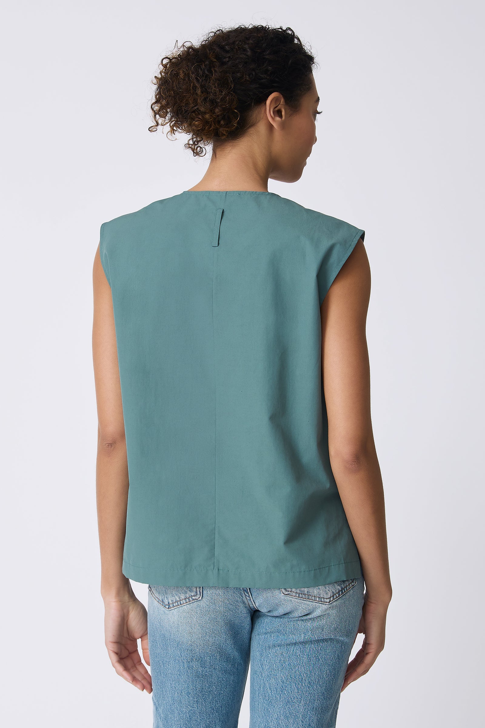 Ava V-Neck Shell Top in Sage on model with hand in back pocket front view