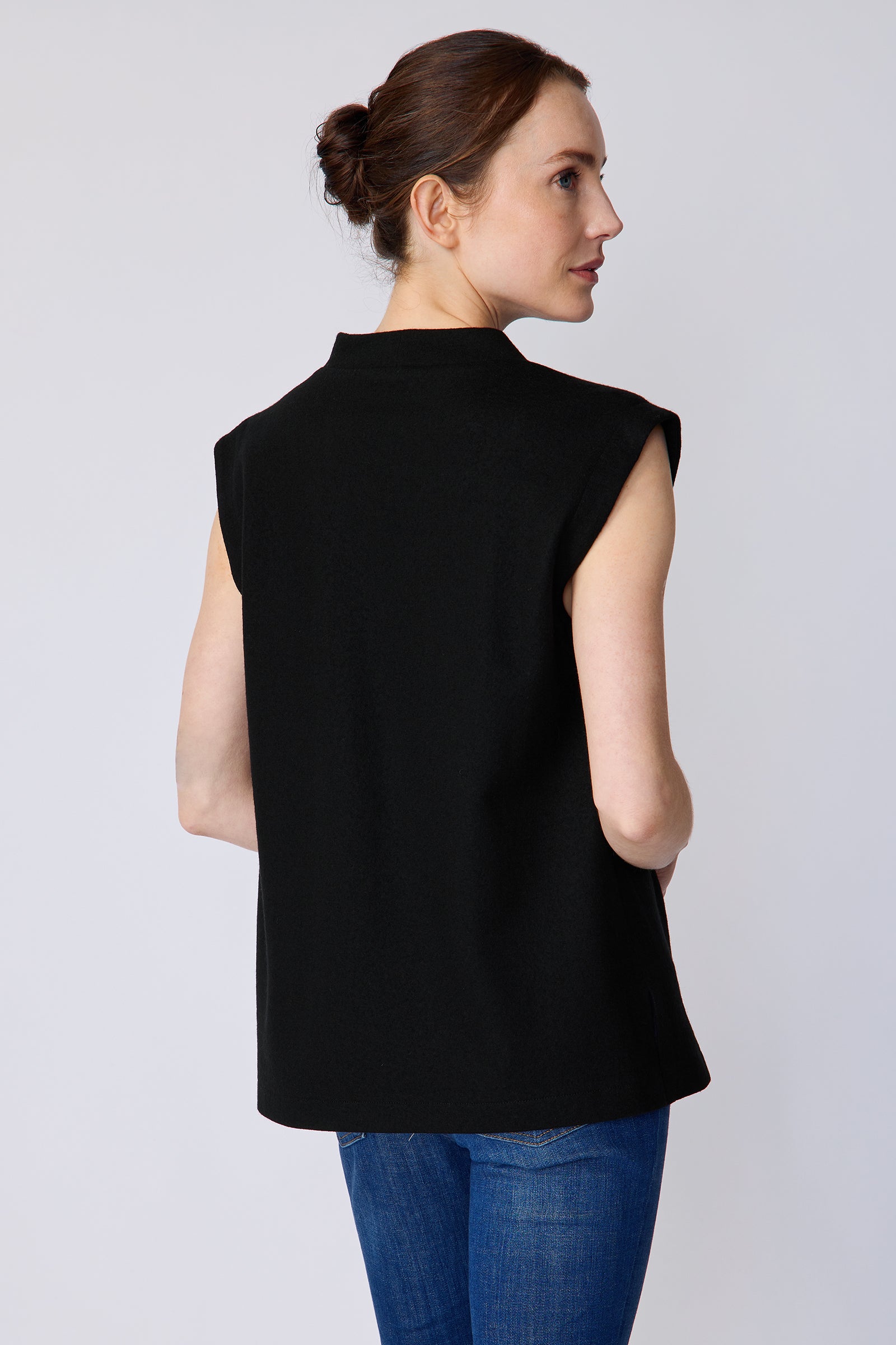 Woman wearing Kal Rieman Arla Drape Top in Black Felted Jersey with blue jeans, arms on the side, close view