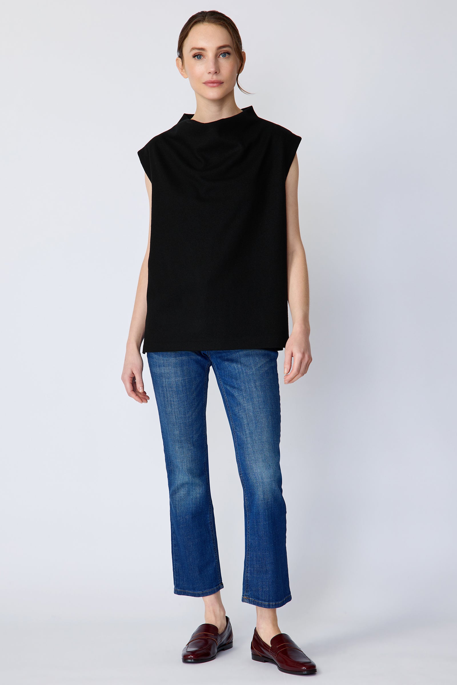 Woman wearing Kal Rieman Arla Drape Top in Black Felted Jersey with blue jeans and brown shoes, arms on the side