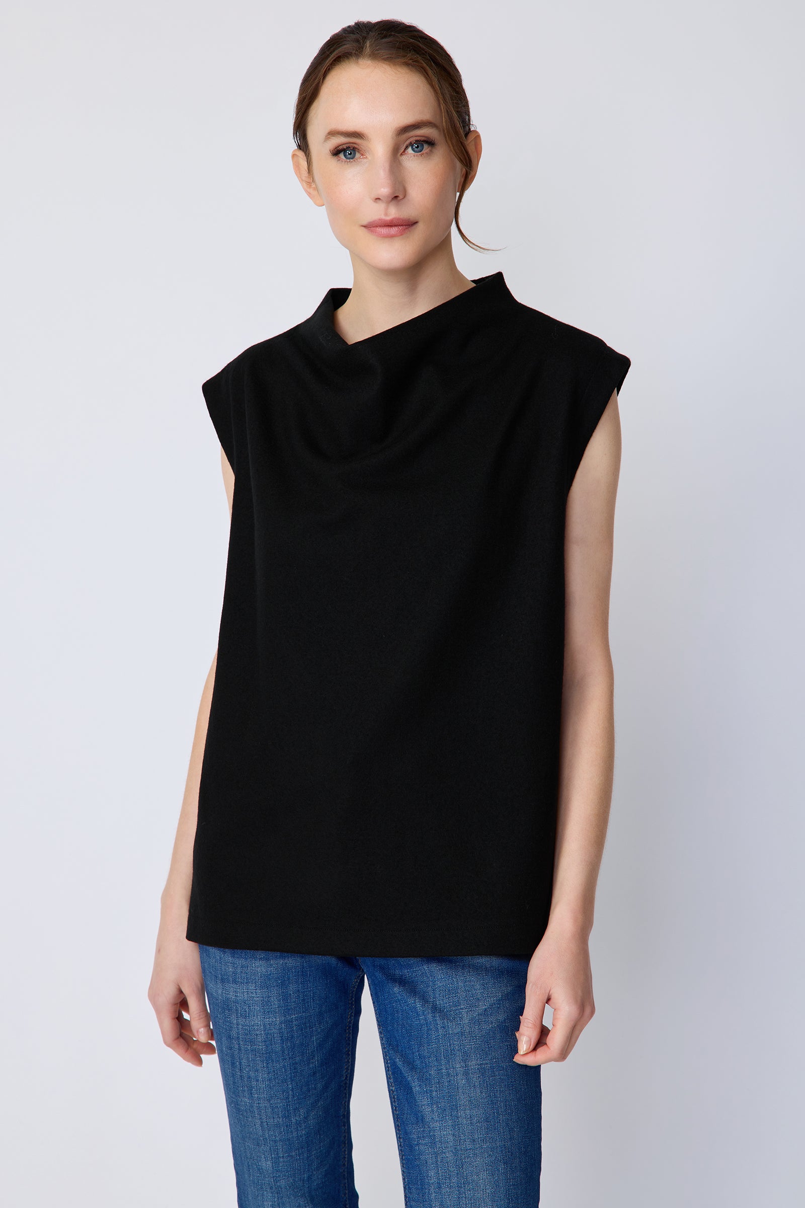 Woman wearing Kal Rieman Arla Drape Top in Black Felted Jersey with blue jeans, arms on the side, close view