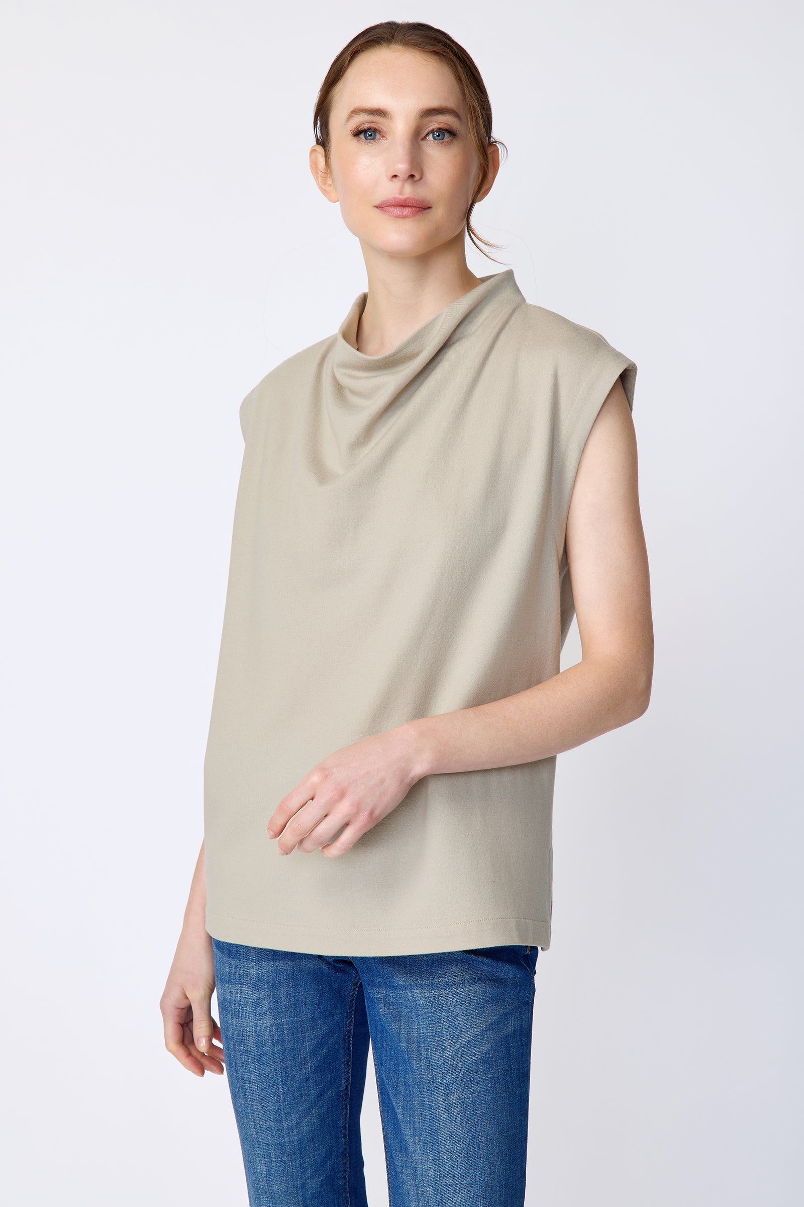 Woman wearing Kal Rieman Arla Drape Top in Mink Felted Jersey and blue jeans on a white background, hand in front close view