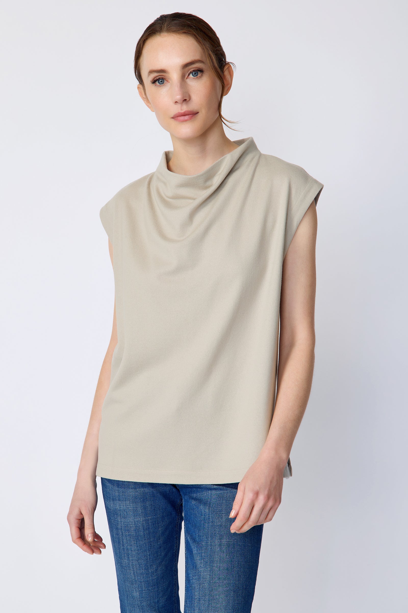 Woman wearing Kal Rieman Arla Drape Top in Mink Felted Jersey and blue jeans on a white background, hand in front close view in movement