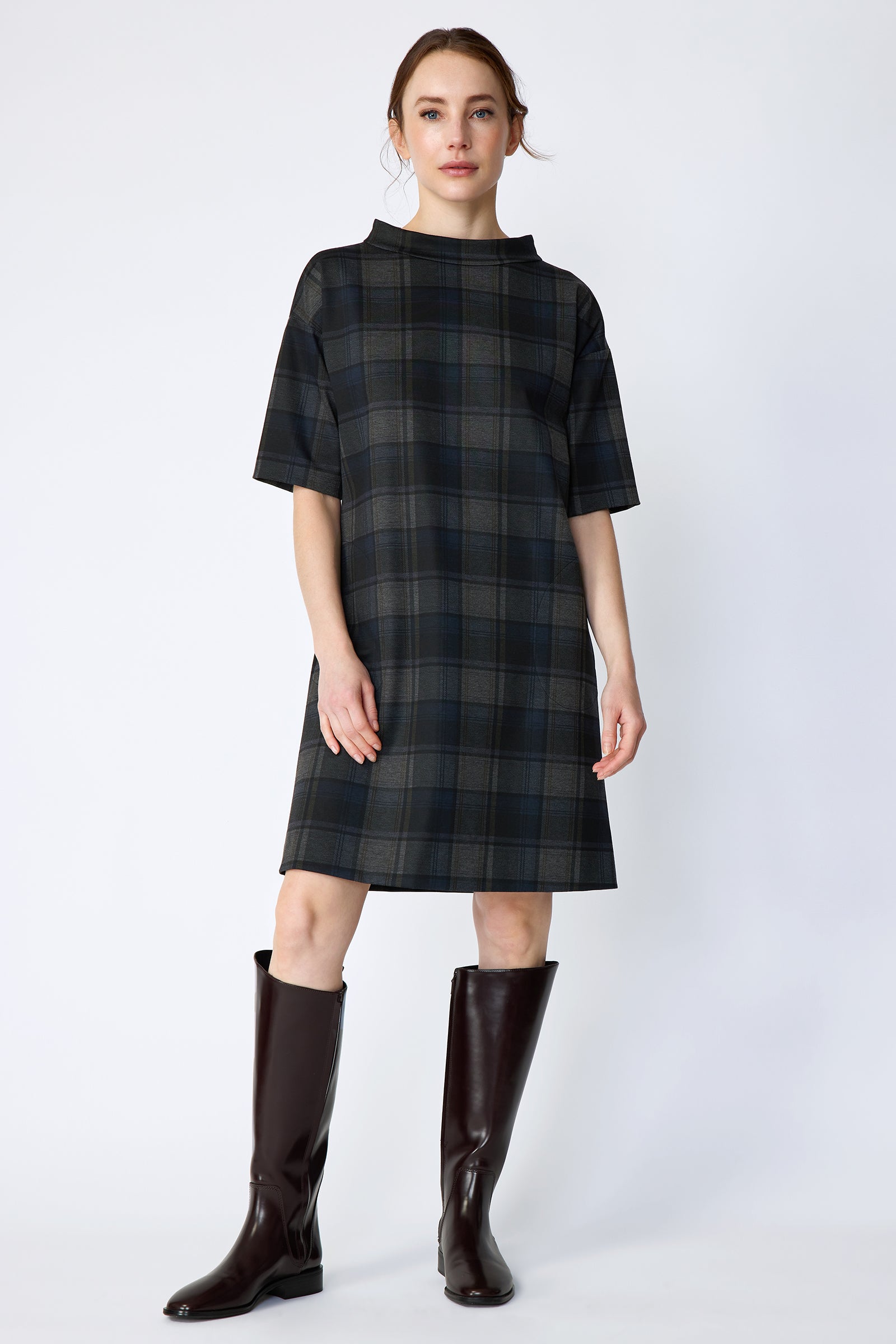 Woman wearing Kal Rieman Avery Shift Dress in Novelty Plaid with knee-high boots on a white background arms on the side