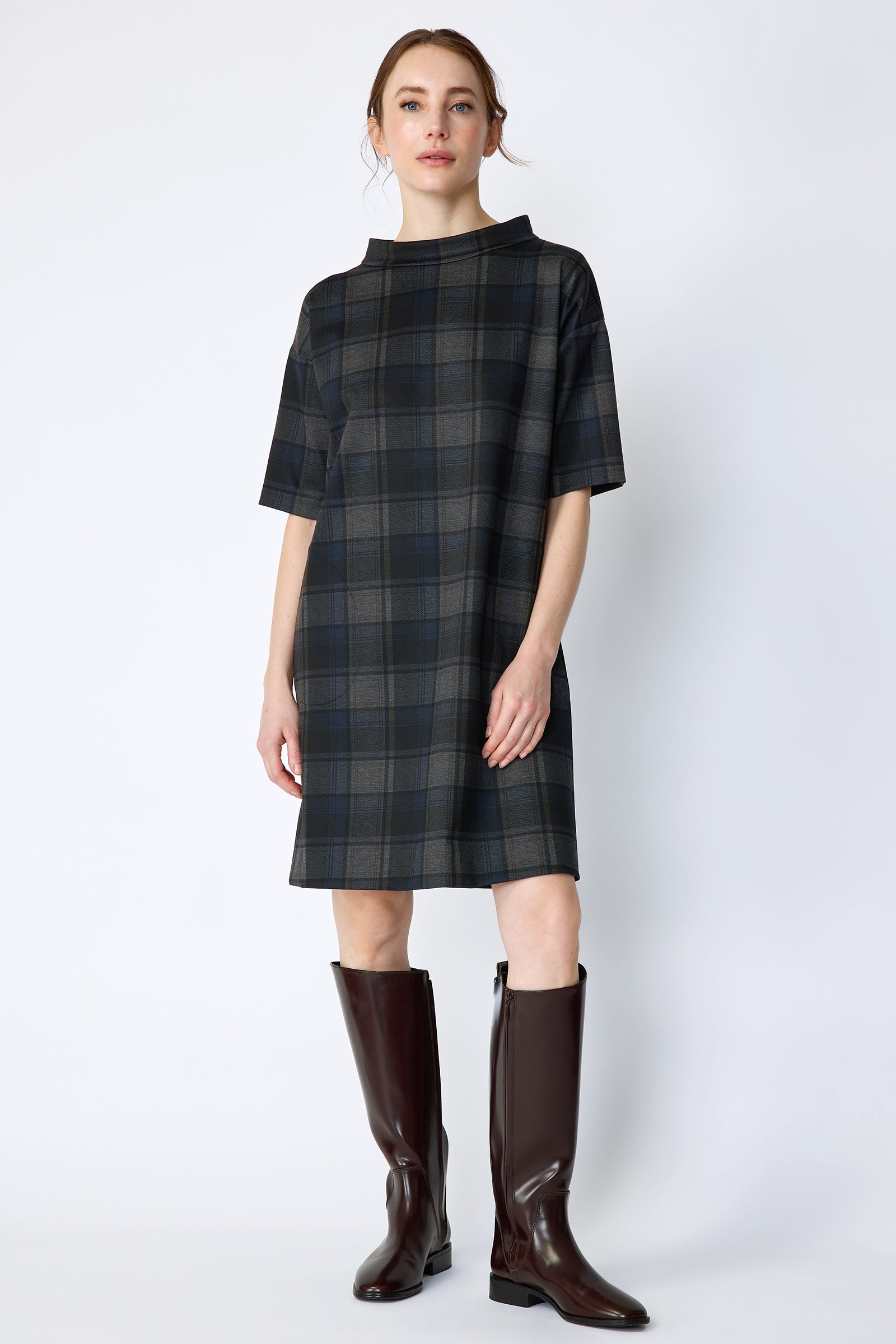 Woman wearing Kal Rieman Avery Shift Dress in Novelty Plaid with knee-high boots on a white background arms on the side