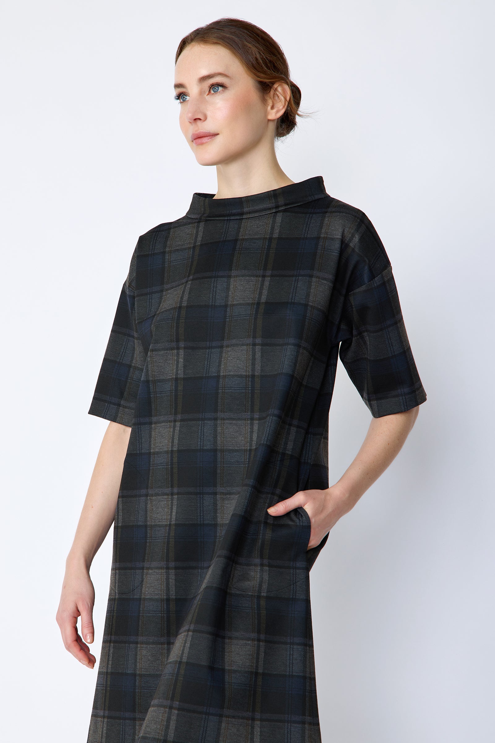Woman wearing Kal Rieman Avery Shift Dress in Novelty Plaid with knee-high boots on a white background arm in pocket, close view