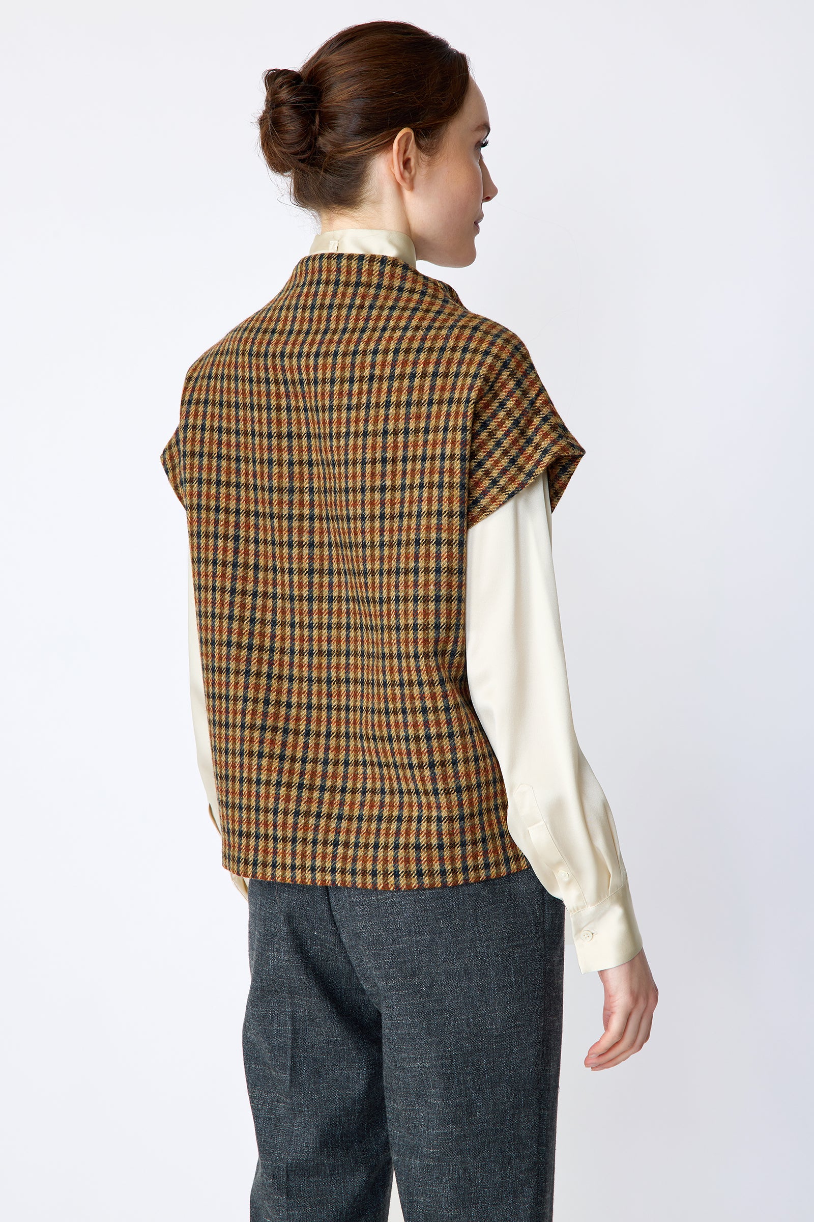 Woman wearing Kal Rieman Bruna Zip Vest in Heritage Check over a Kal Rieman Silk Regency Blouse in Oyster with a white background, arms on the side, back view