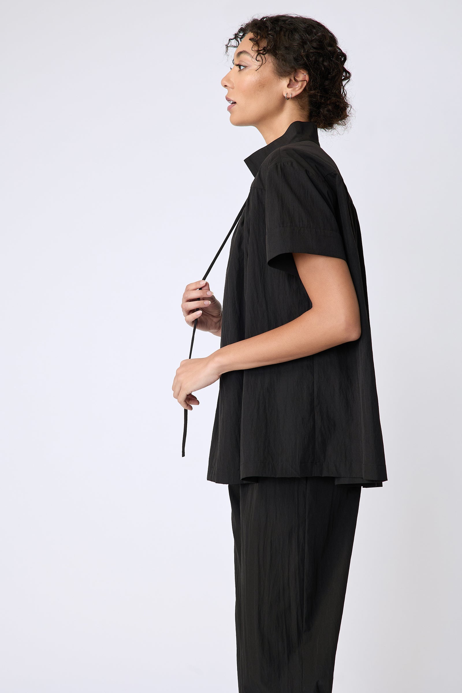 Kal Rieman Camille Top in black typewriter cloth on model side view holding string