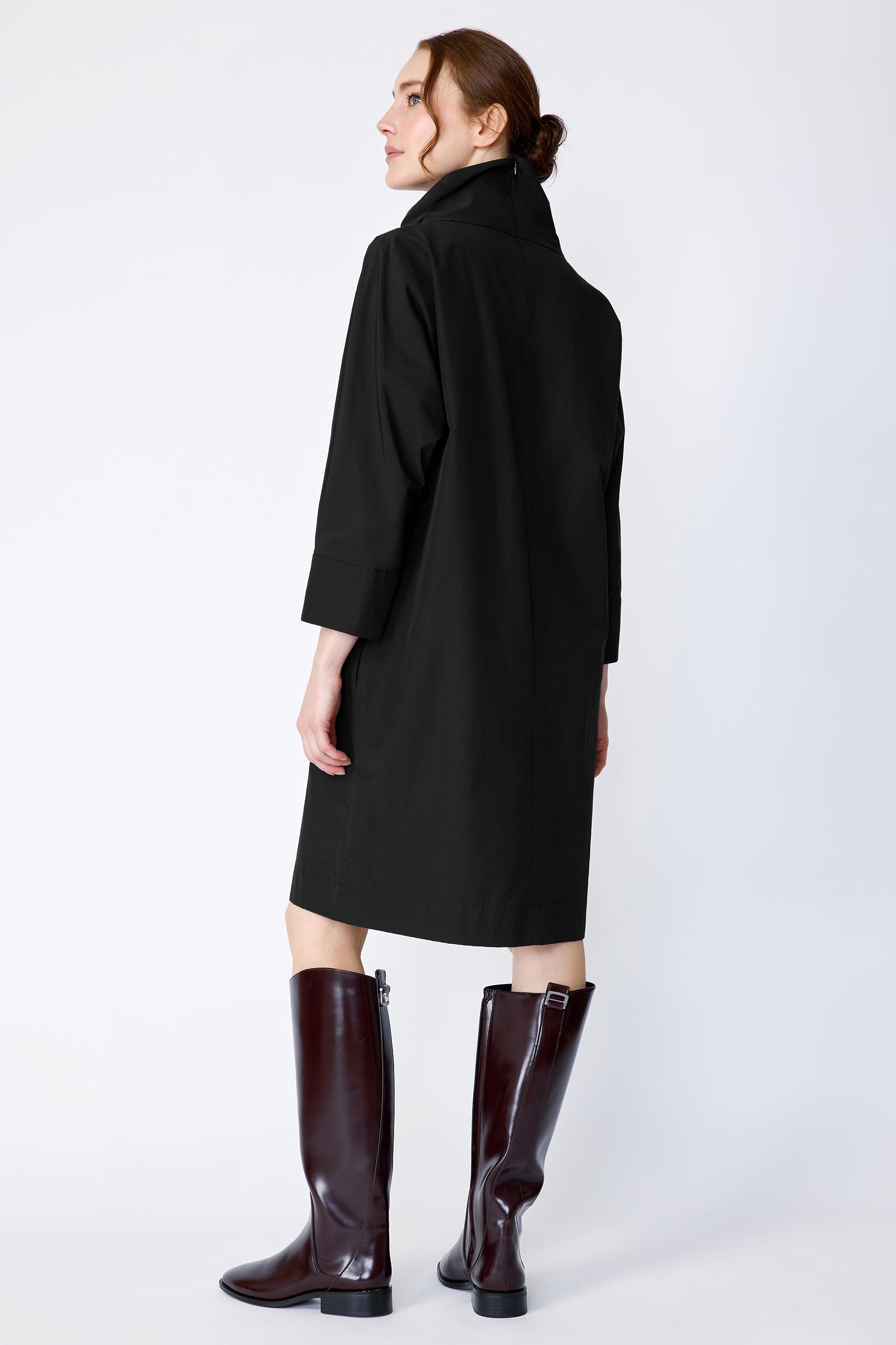 Woman wearing Kal Rieman Carla black dress and brown boots on a white background