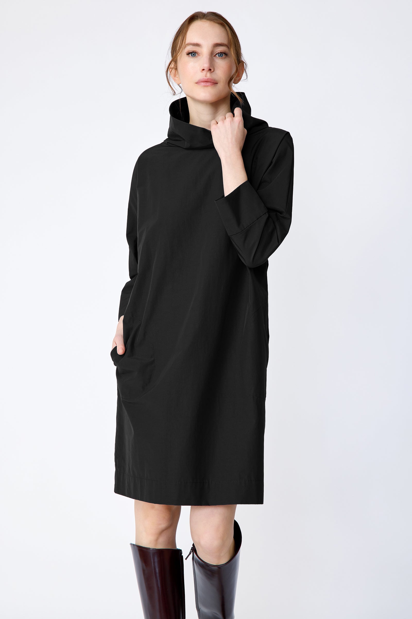 Woman wearing Kal Rieman Carla black dress and brown boots on a white background holding collar