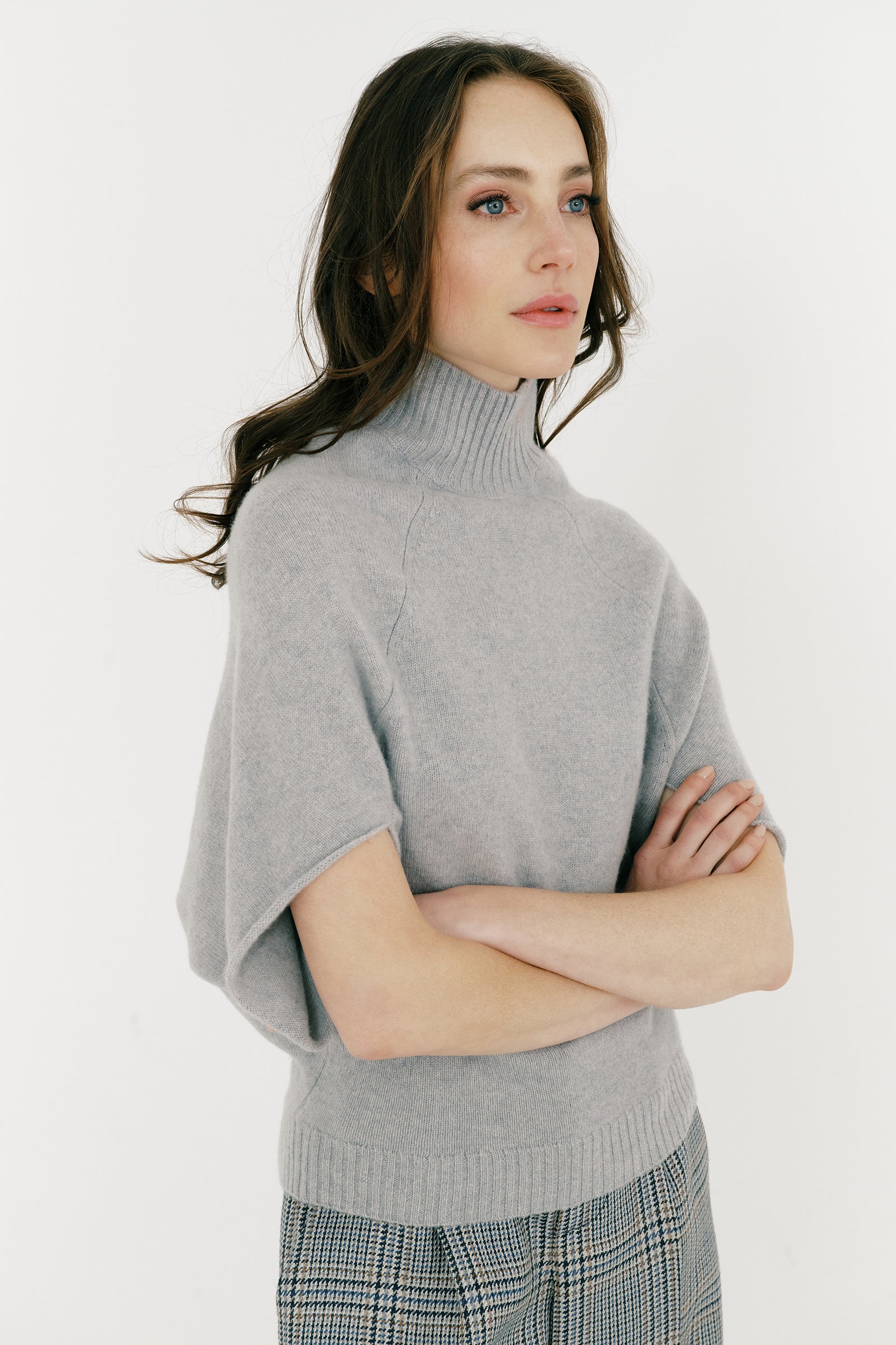 Woman wearing Kal Rieman Cashmere Cape Sweater in Heather Grey with a white background arms crossed in front