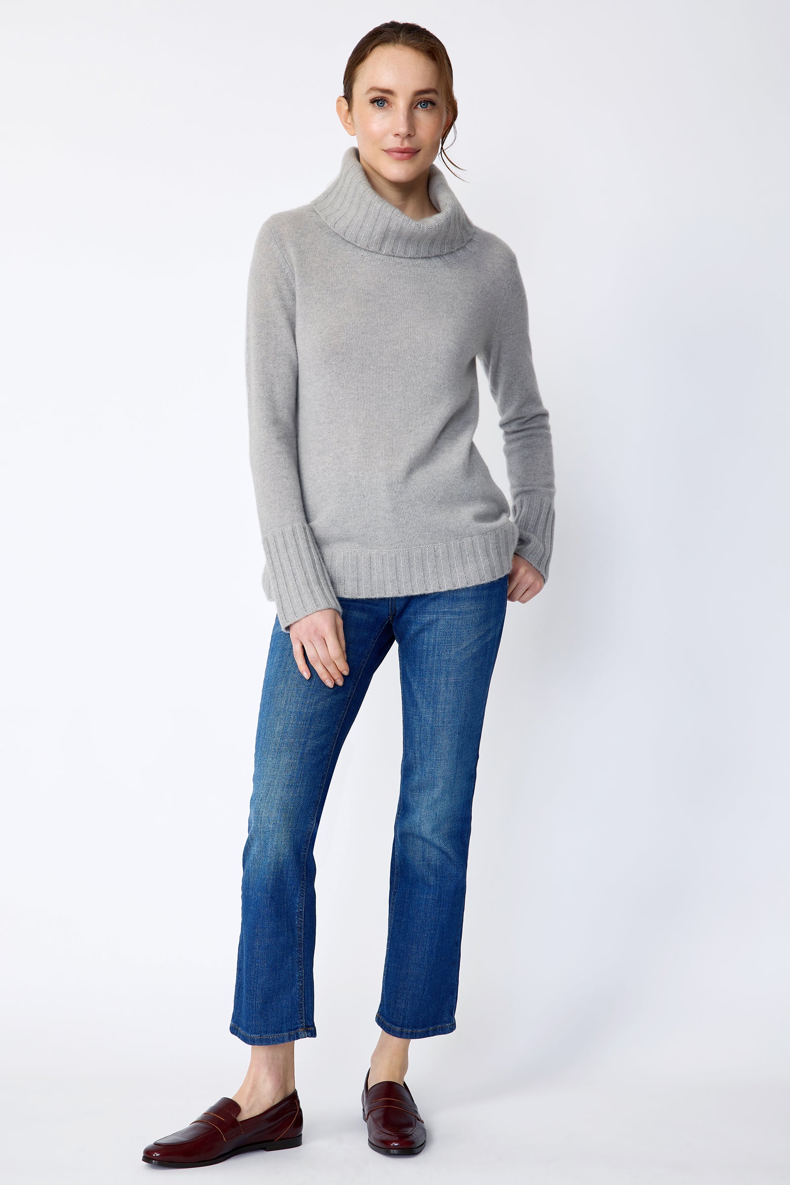 Woman wearing Kal Rieman Cashmere Cowl Tneck in Heather Grey and blue jeans on a white background arm in back pocket