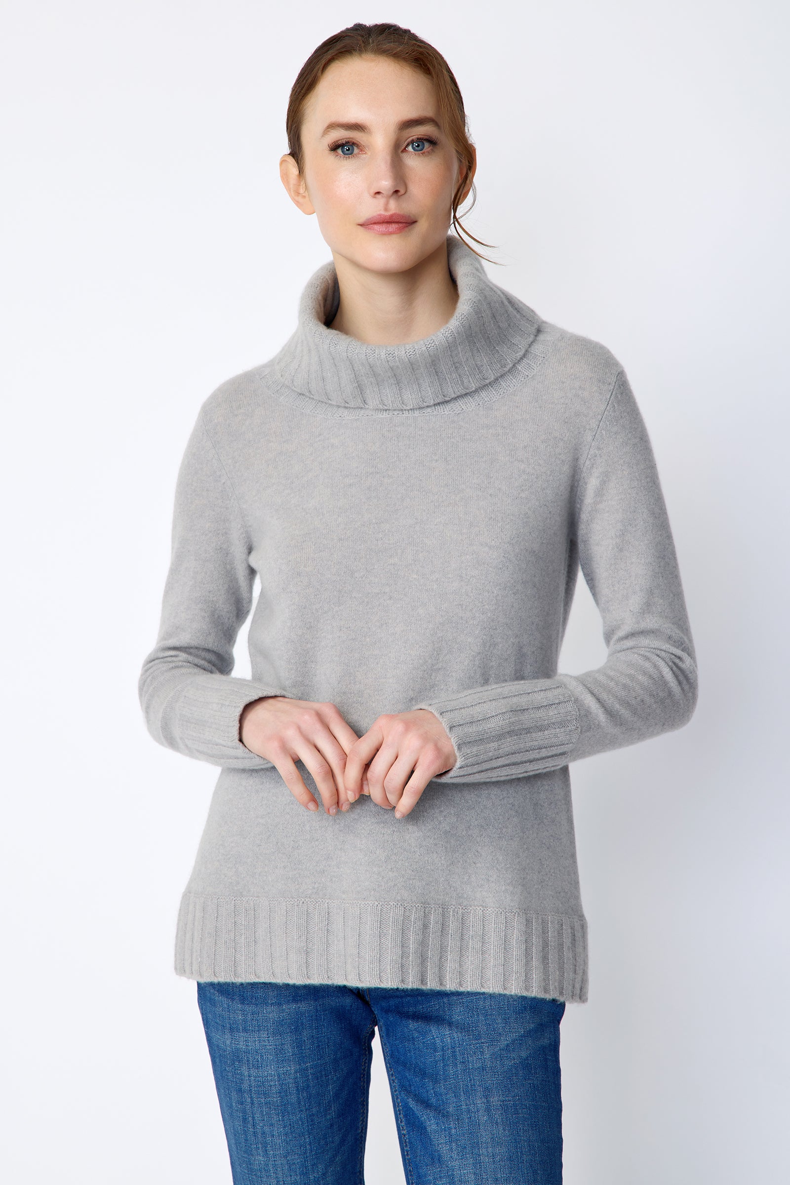 Woman wearing Kal Rieman Cashmere Cowl Tneck in Heather Grey and blue jeans on a white background arms holding in front close view