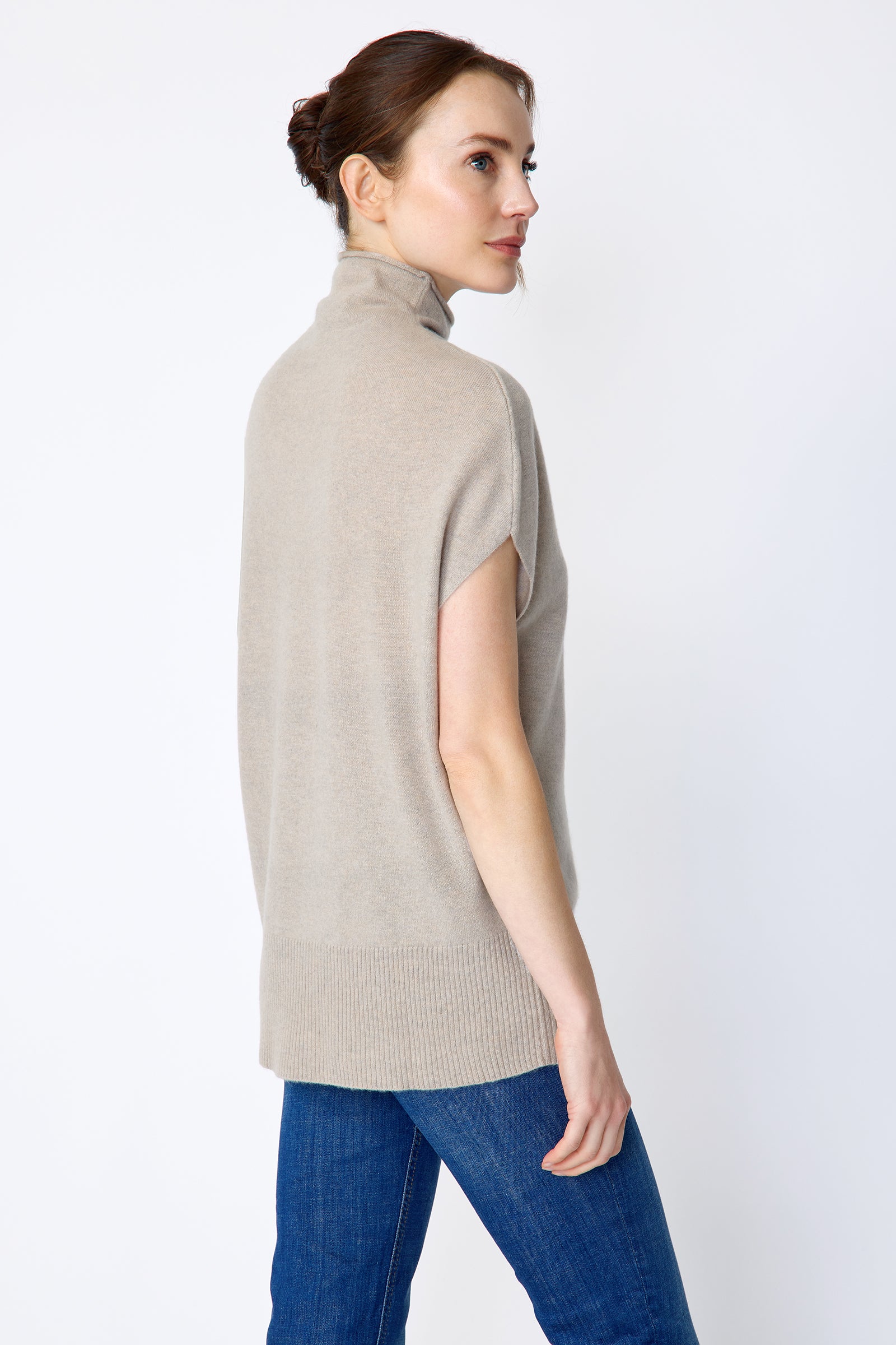 Woman wearing Kal Rieman Cashmere Funnelneck in Drift and blue jeans on a white background, arms on the side back view