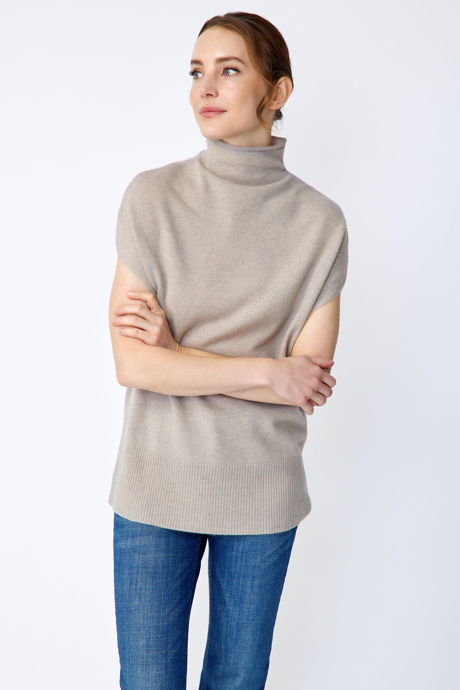 Woman wearing Kal Rieman Cashmere Funnelneck in Drift and blue jeans on a white background, arms crossed in front close view