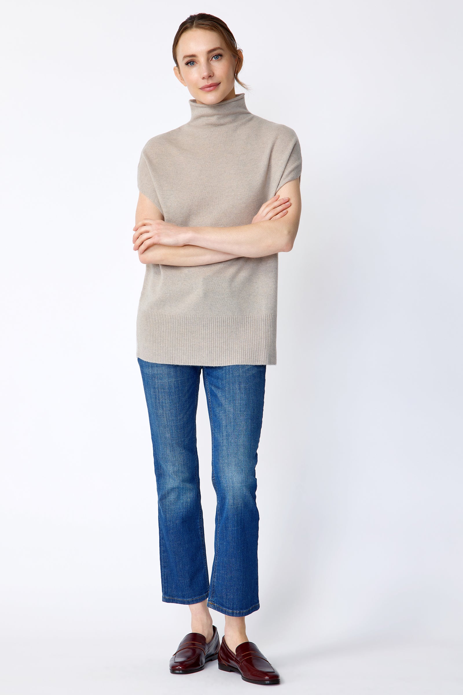 Woman wearing Kal Rieman Cashmere Funnelneck in Drift and blue jeans on a white background, arms crossed in front