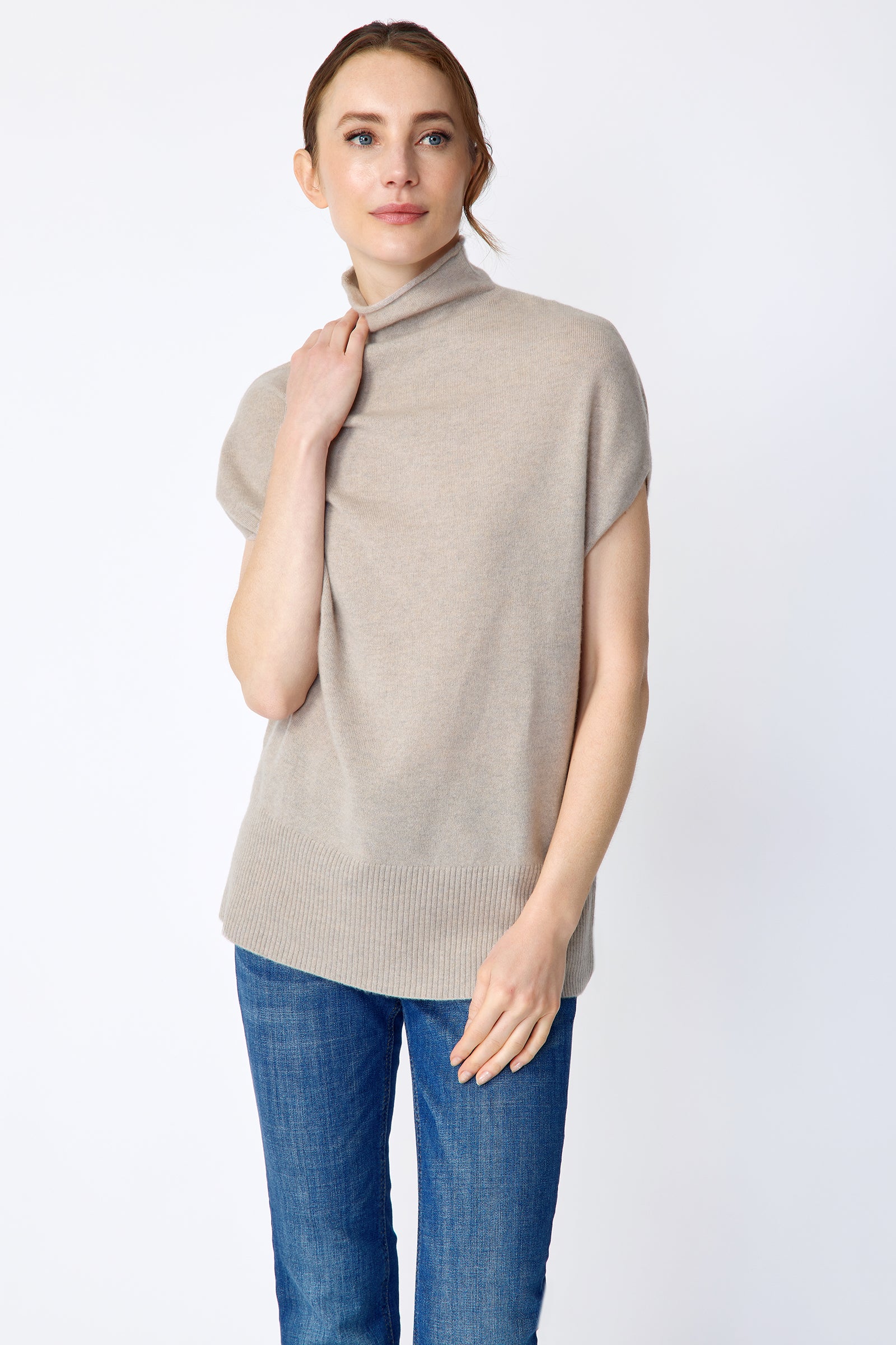 Woman wearing Kal Rieman Cashmere Funnelneck in Drift and blue jeans on a white background, arms on shoulder close view