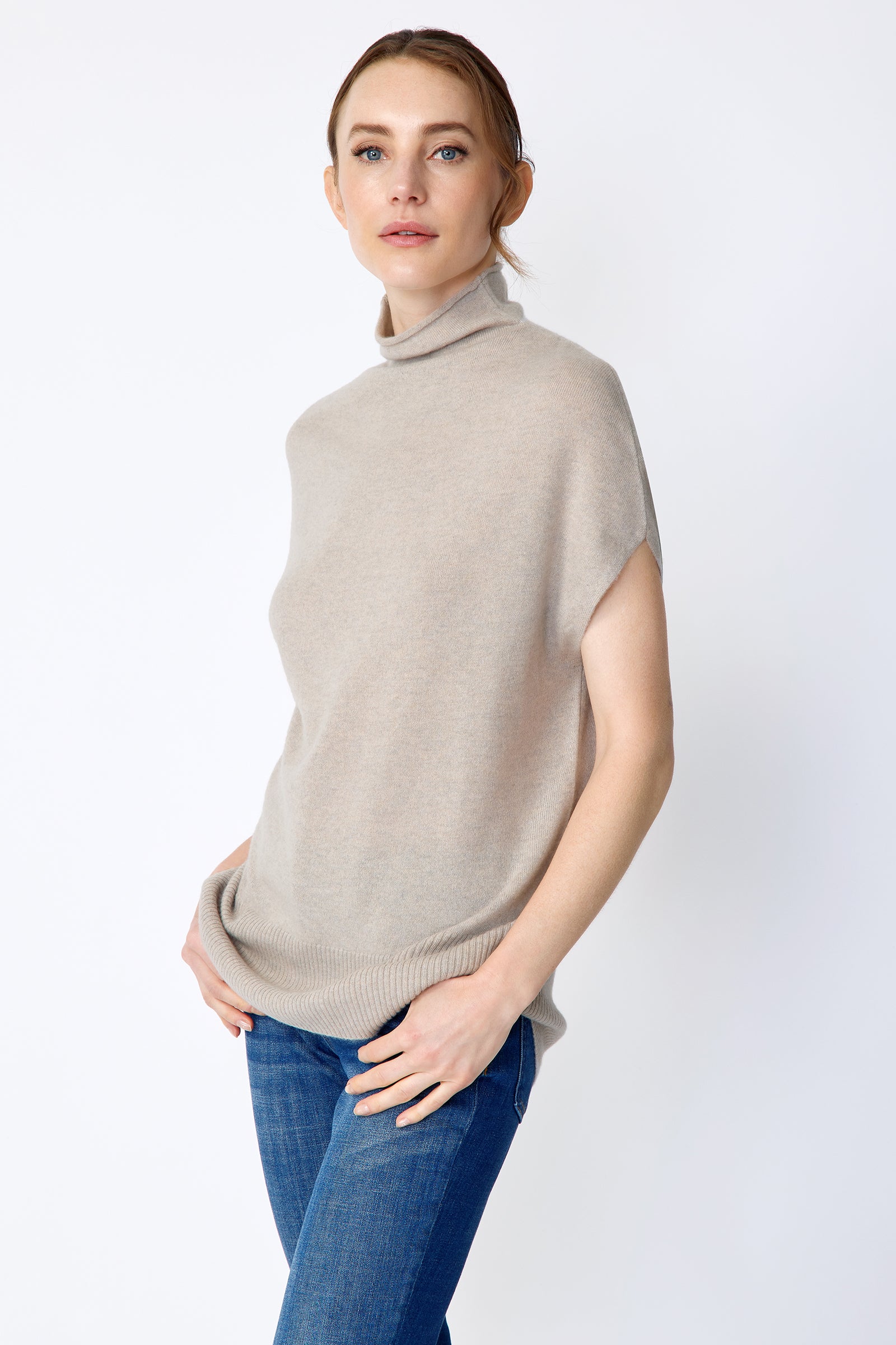 Woman wearing Kal Rieman Cashmere Funnelneck in Drift and blue jeans on a white background, hands in pockets
