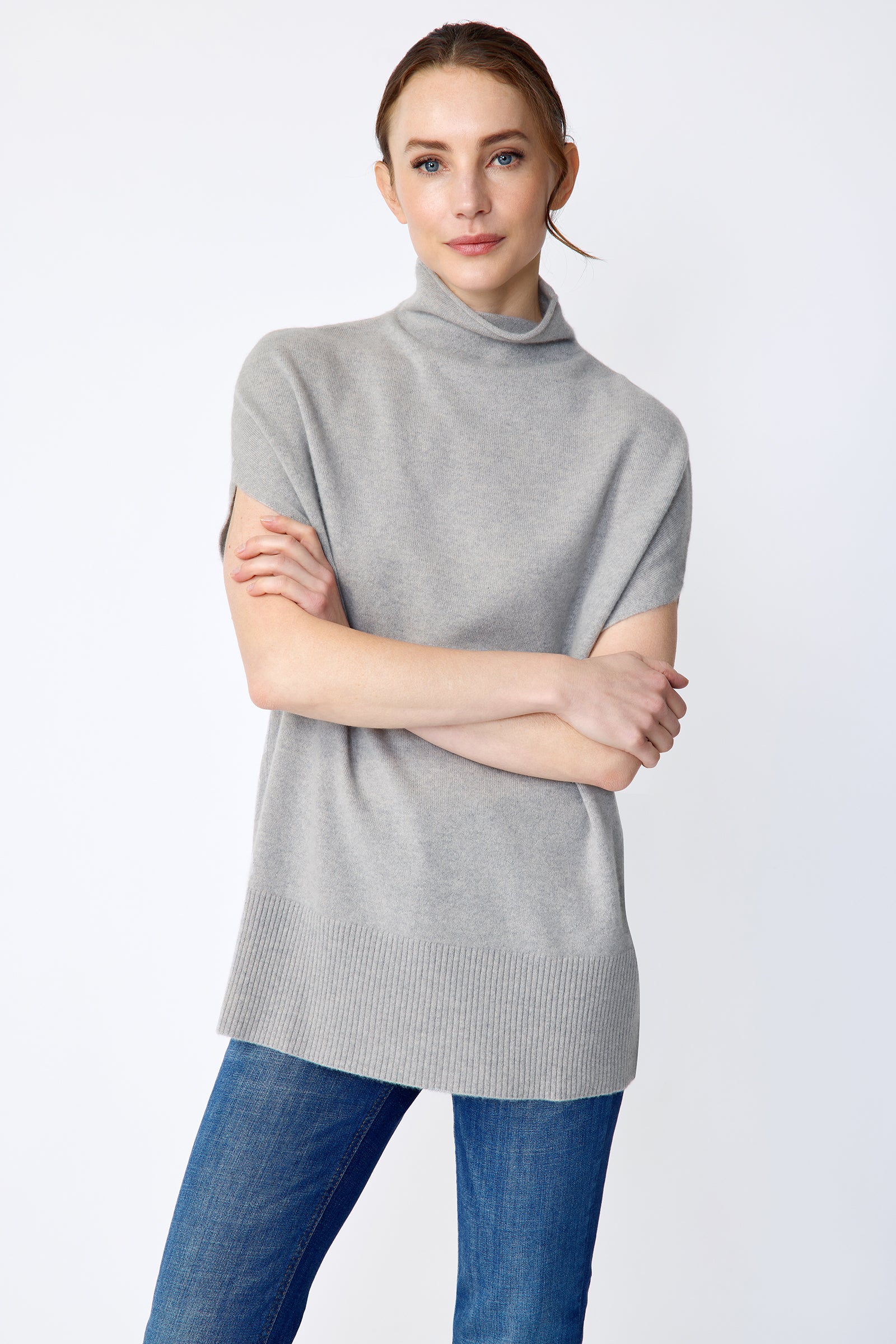 Woman wearing Kal Rieman Cashmere Funnelneck in Heather gray, blue jeans, and brown shoes on a white background arms crossed in front close view
