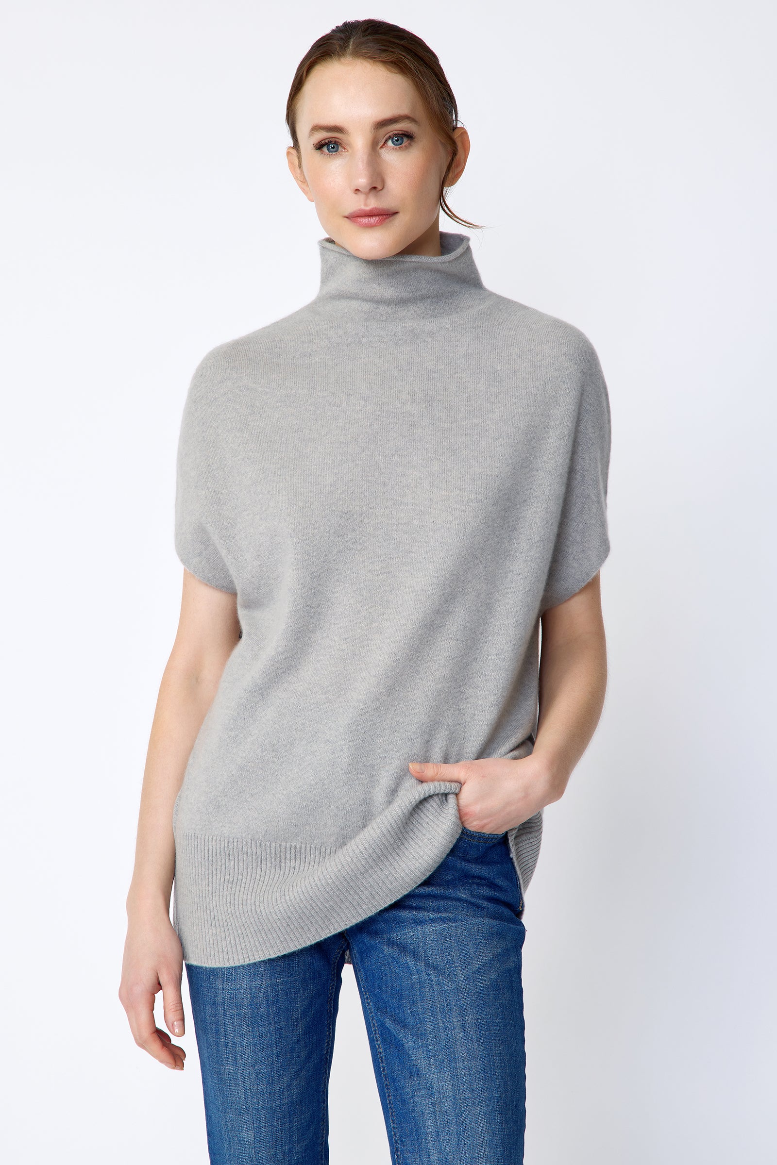Woman wearing Kal Rieman Cashmere Funnelneck in Heather gray and blue jeans on a white background hand in pocket, arm on the side, close view