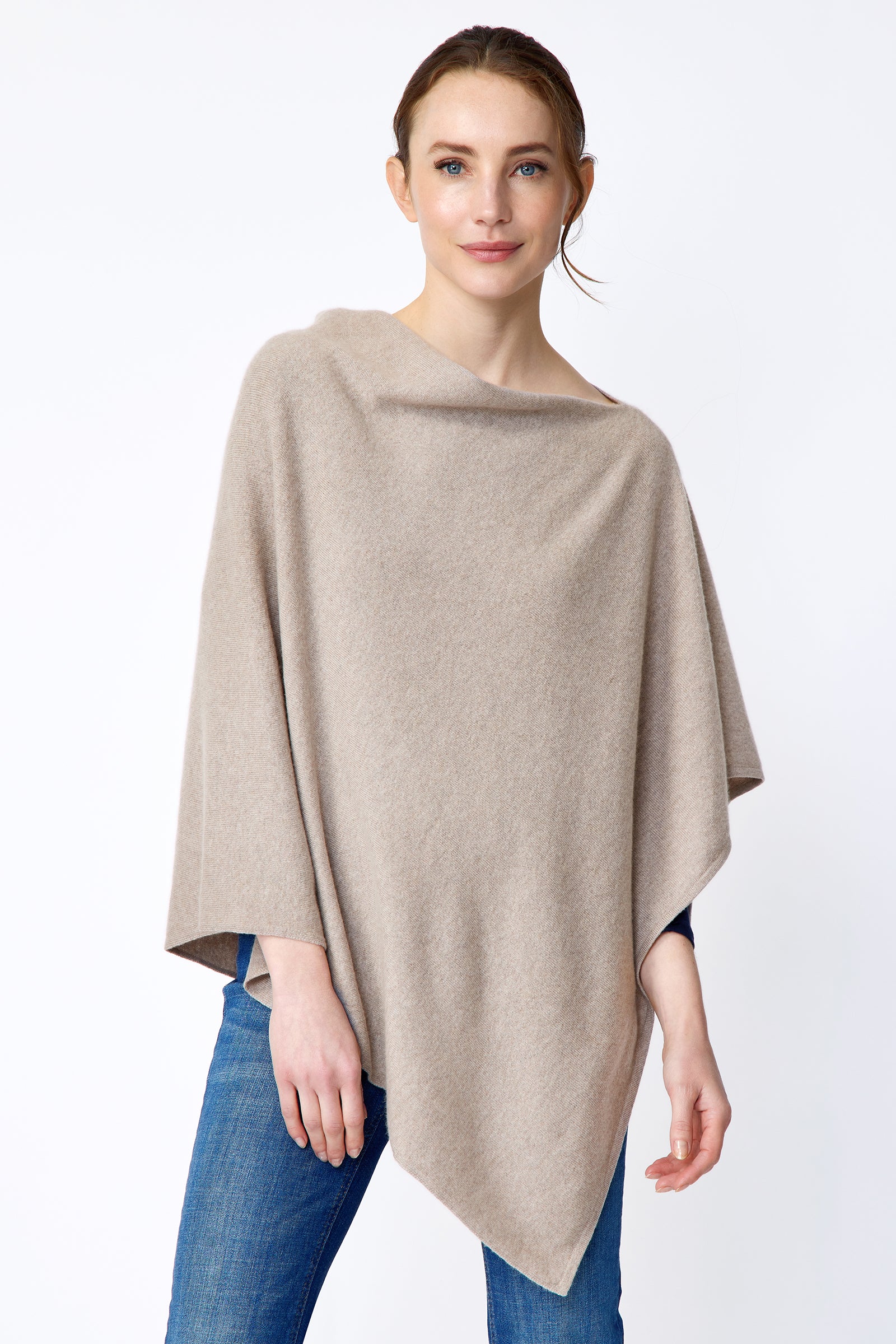 Woman wearing Kal Rieman Poncho in Drift over a blue top and blue jeans on a white background