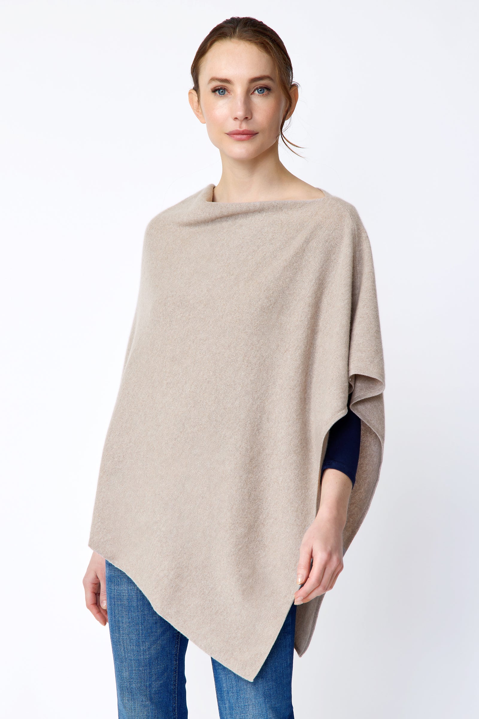 Woman wearing Kal Rieman Poncho in Drift over a blue top and blue jeans on a white background arms in movement close view