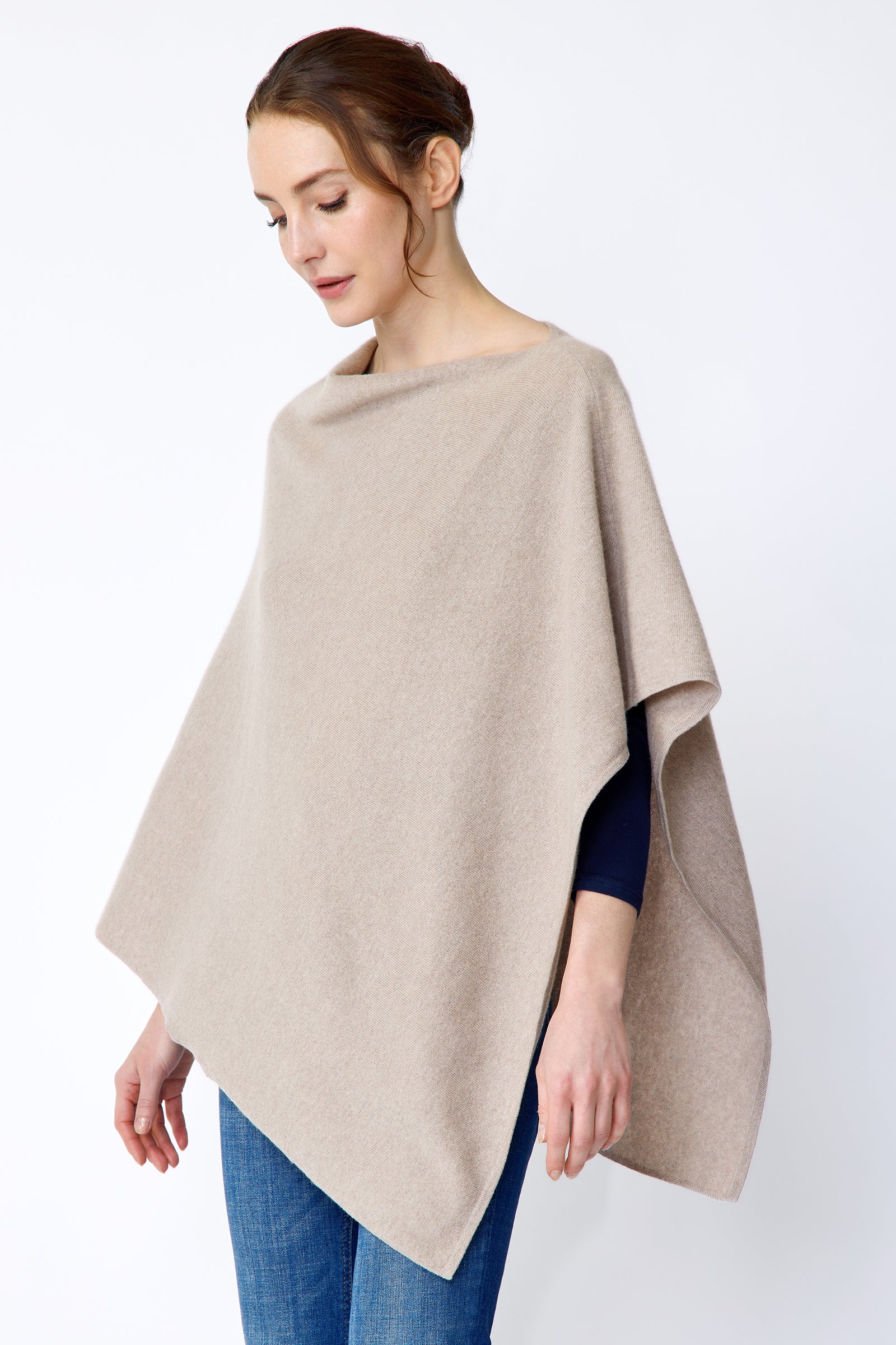 Woman wearing Kal Rieman Poncho in Drift over a blue top and blue jeans on a white background side view arms in movement