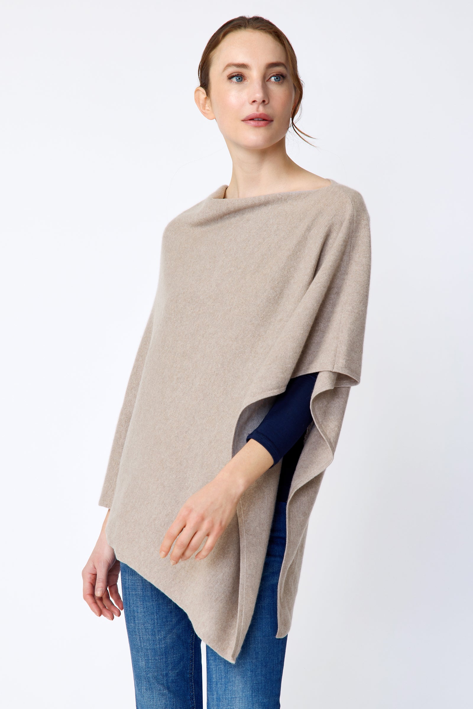 Woman wearing Kal Rieman Poncho in Drift over a blue top and blue jeans on a white background side view
