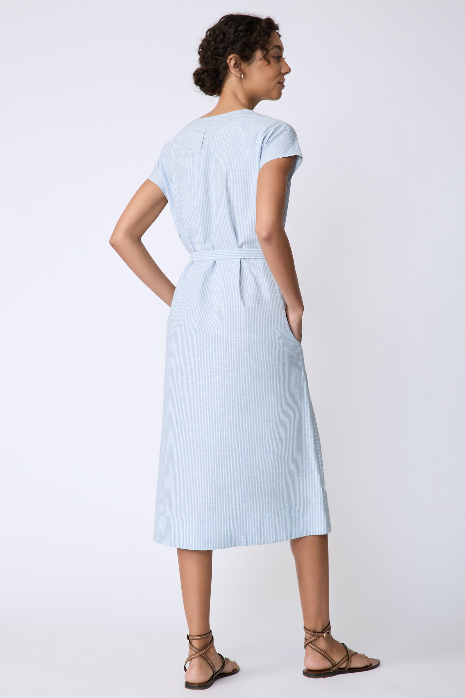 Kal Rieman Clara Dress in light blue mini stripe on model back view hands in pockets