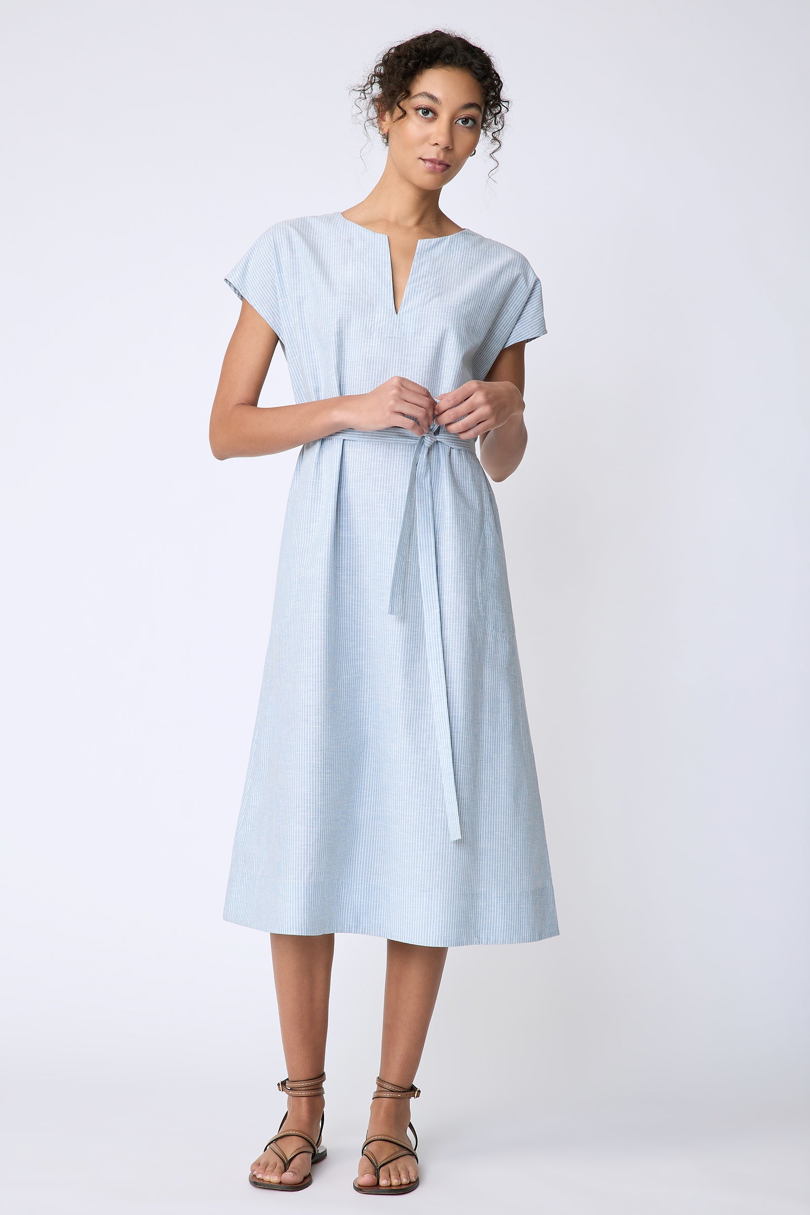 Kal Rieman Clara Dress in light blue mini stripe on model front view holding tie