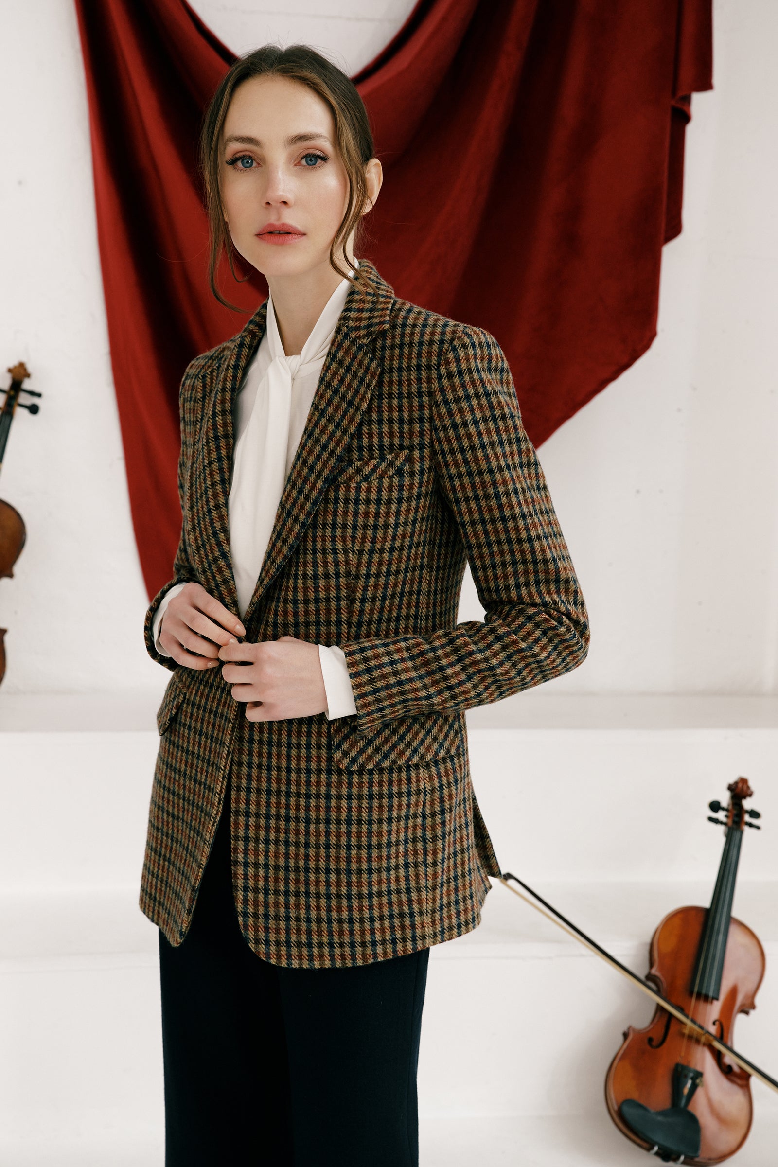 Woman wearing Kal Rieman Classic Tailored Blazer in Heritage Check over Kal Rieman Cecilia Scarf Top in Ivory with black pants, arms on the side, looking sideways