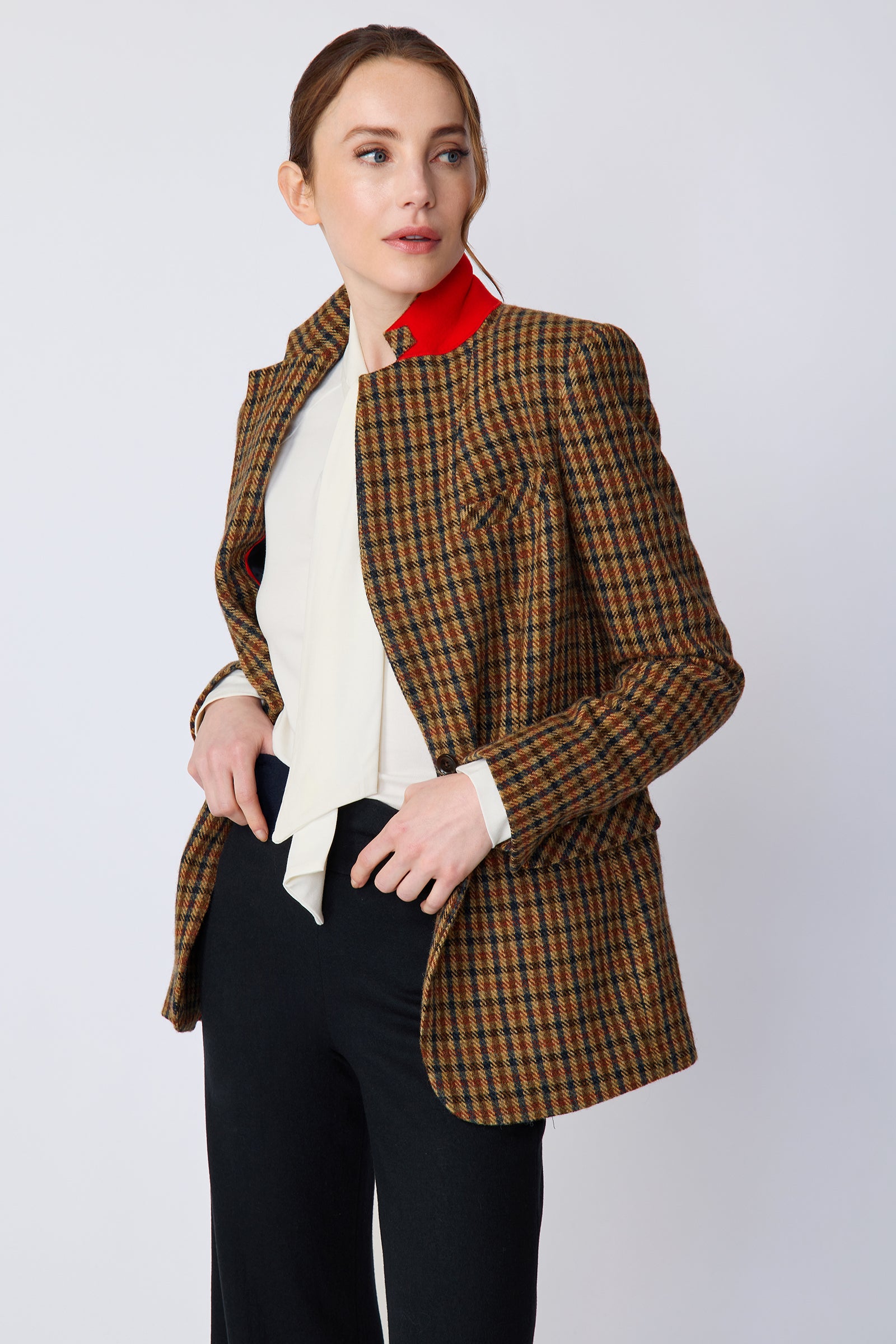 Woman wearing Kal Rieman Classic Tailored Blazer in Heritage Check over Kal Rieman Cecilia Scarf Top in Ivory with black pants, hands in pant pockets, blazer unbuttoned