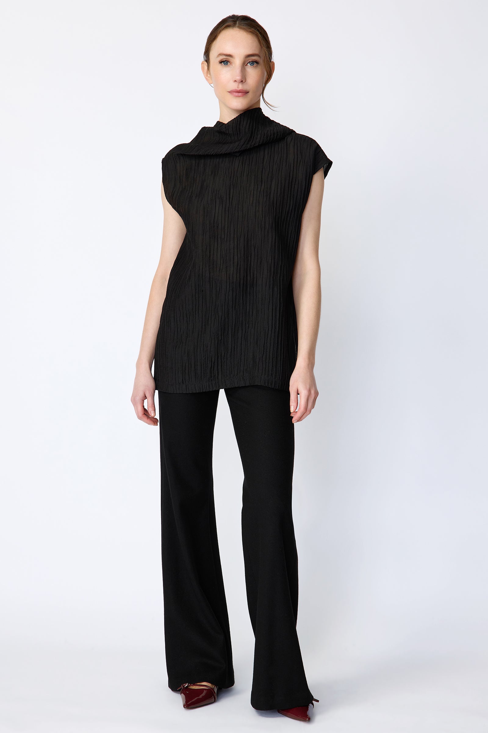 Woman wearing Kal Rieman Claudia Scarf Tunic in Black Taffeta on a white background, arms on the side