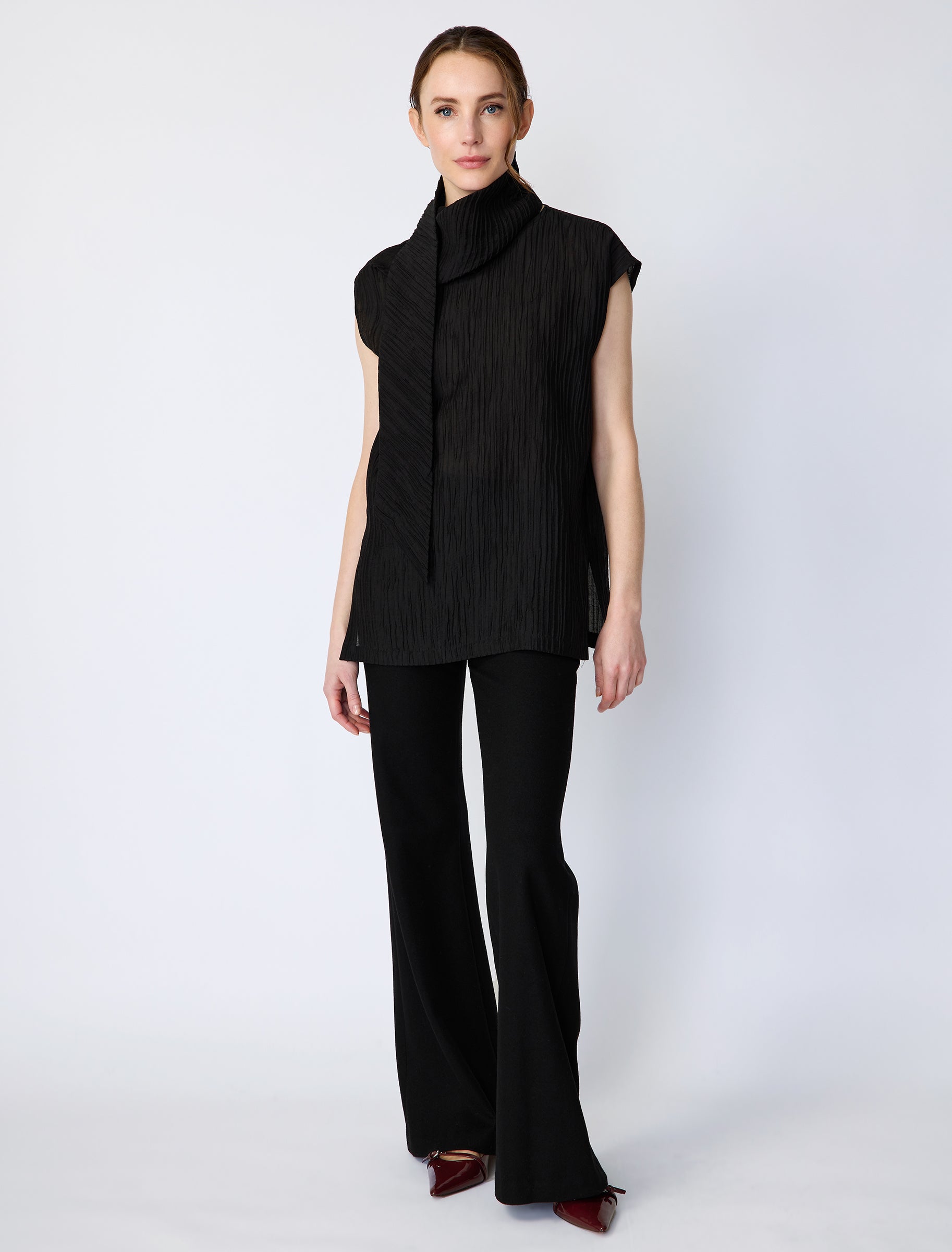 Woman wearing Kal Rieman Claudia Scarf Tunic in Black Taffeta on a white background, arms on the side
