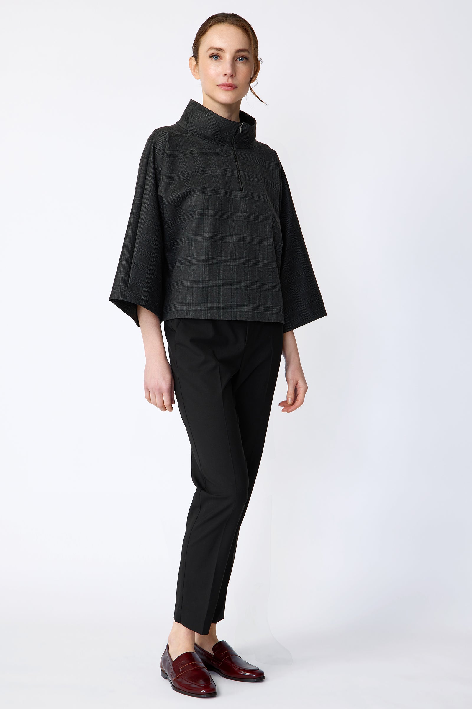 Woman wearing the Kal Rieman Edith Kimono Top in Black Glen Plaid and black pants on a white background arms on the side