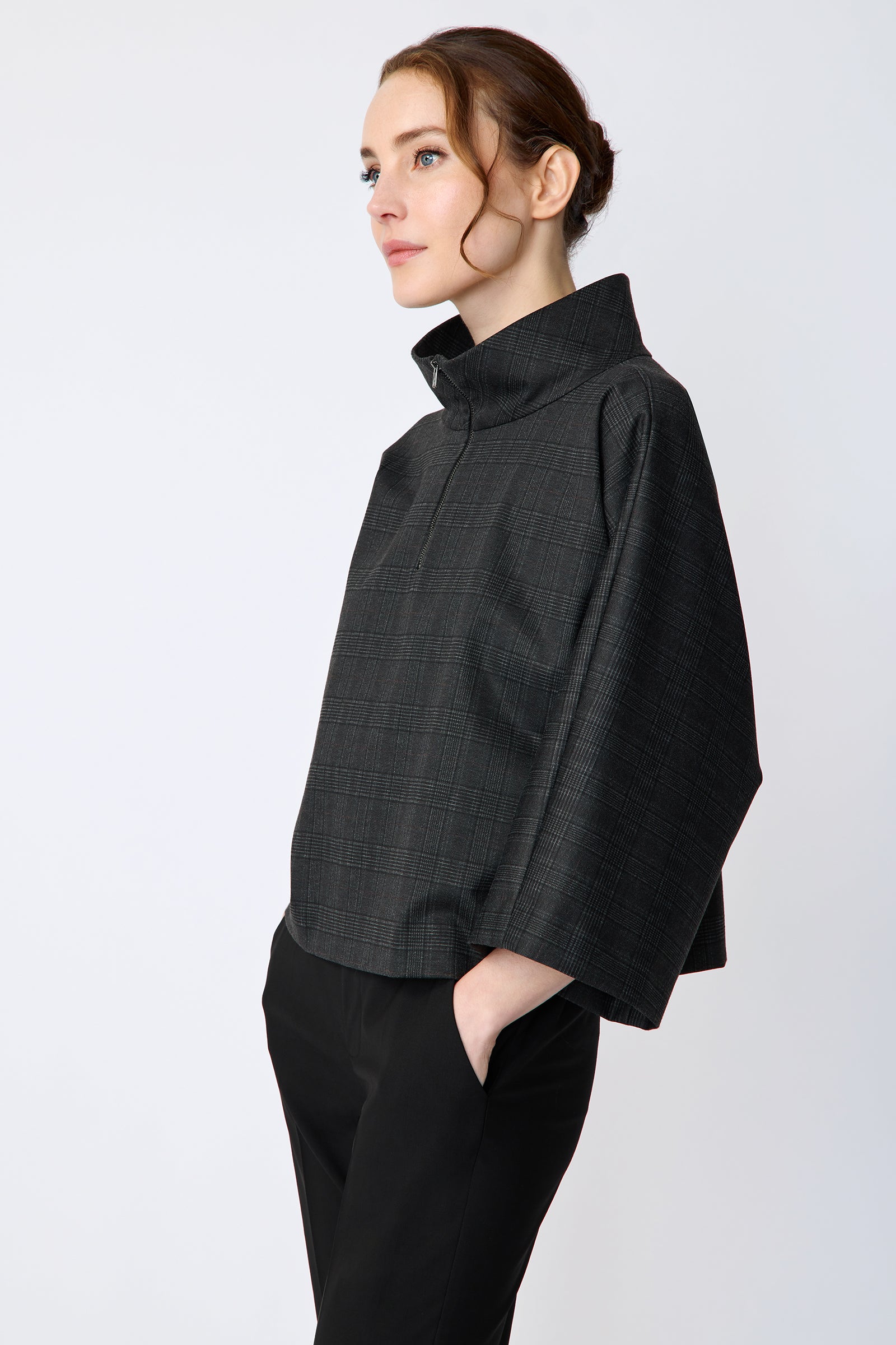Woman wearing the Kal Rieman Edith Kimono Top in Black Glen Plaid and black pants on a white background hands in pocket side view