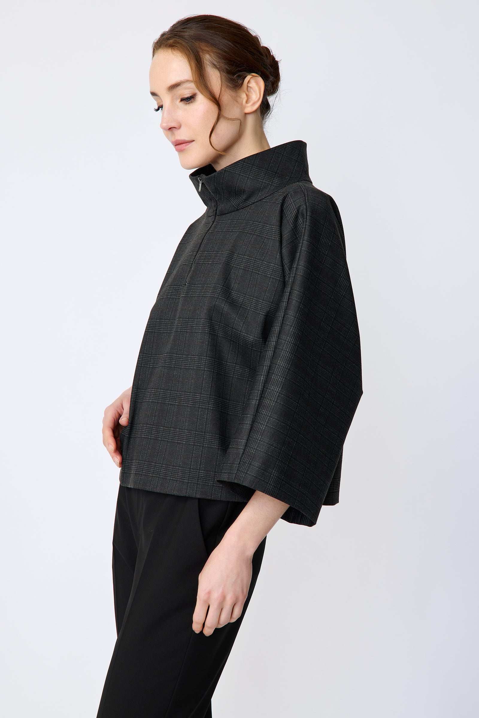 Woman wearing the Kal Rieman Edith Kimono Top in Black Glen Plaid and black pants on a white background arms on the side, side view