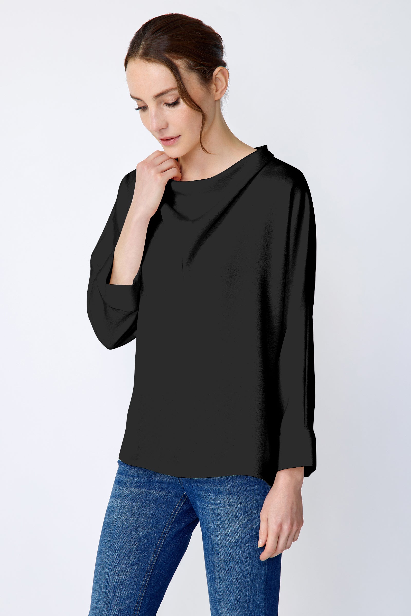 Woman wearing Kal Rieman Elena Drape Top in black satin with blue jeans, holding collar, arm on the side, close front view, looking down