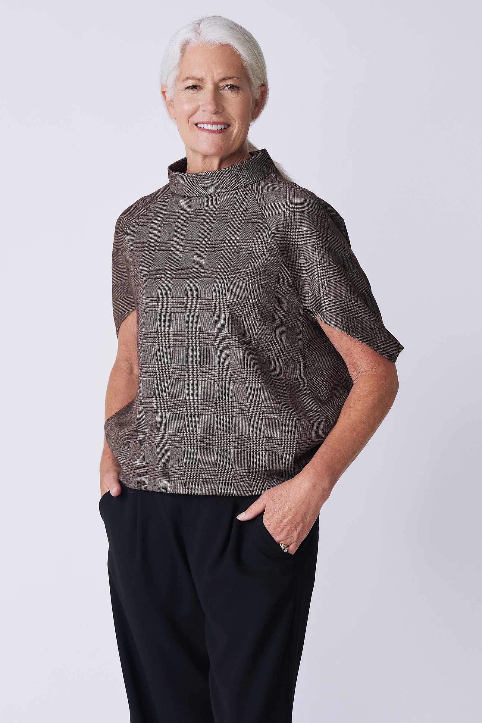 Kal Rieman Elsa Cape Top in brown plaid on model front view hands in pockets