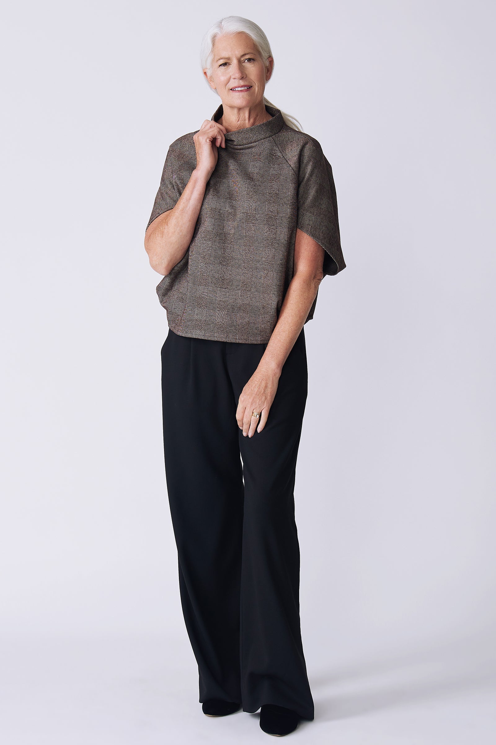 Kal Rieman Elsa Cape Top in brown plaid on model front view holding collar