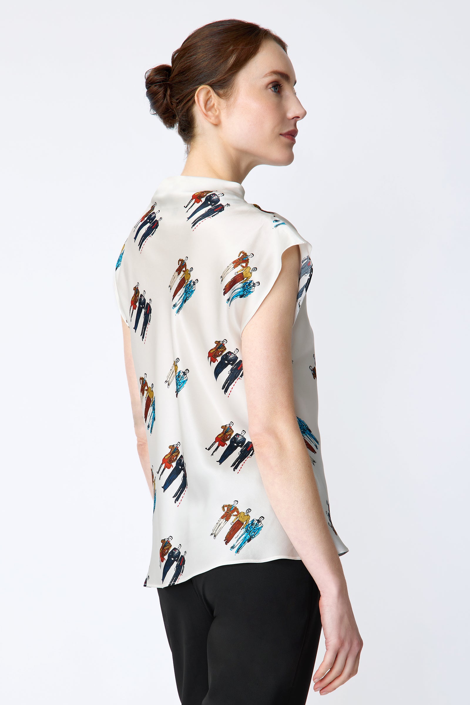 Woman wearing Kal Rieman Gloria Drape Top in Dandy Print and black pants on a white background arms on the side, back view