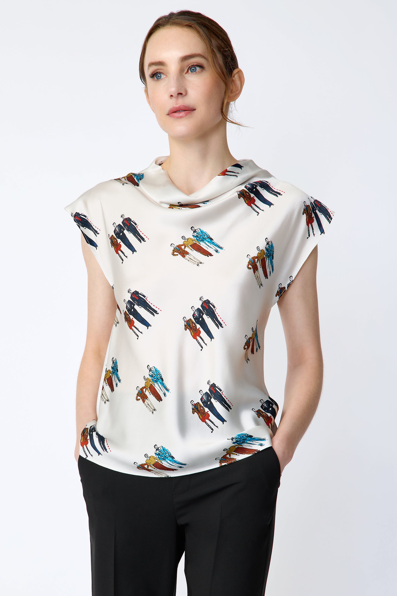 Woman wearing Kal Rieman Gloria Drape Top in Dandy Print and black pants on a white background hands in pockets close view