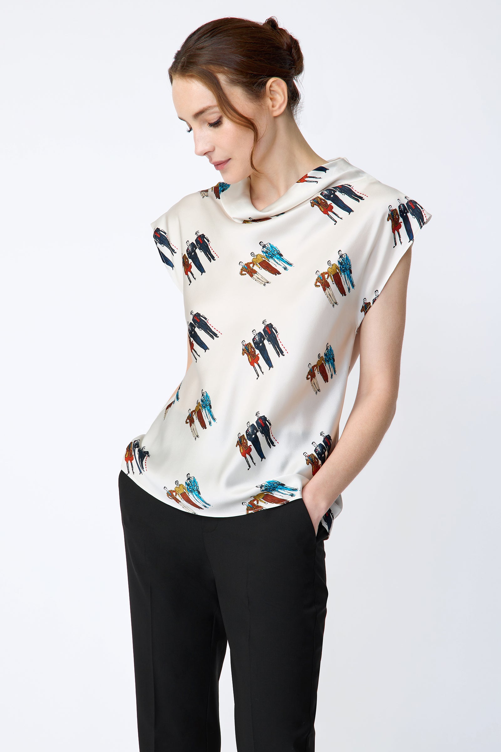Woman wearing Kal Rieman Gloria Drape Top in Dandy Print and black pants on a white background hands in pocket, looking down