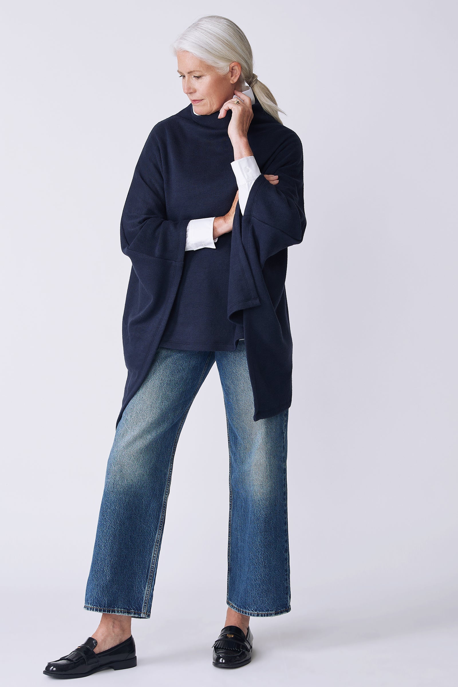 Kal Rieman Jackie Cape in blue knit on model side view holding collar