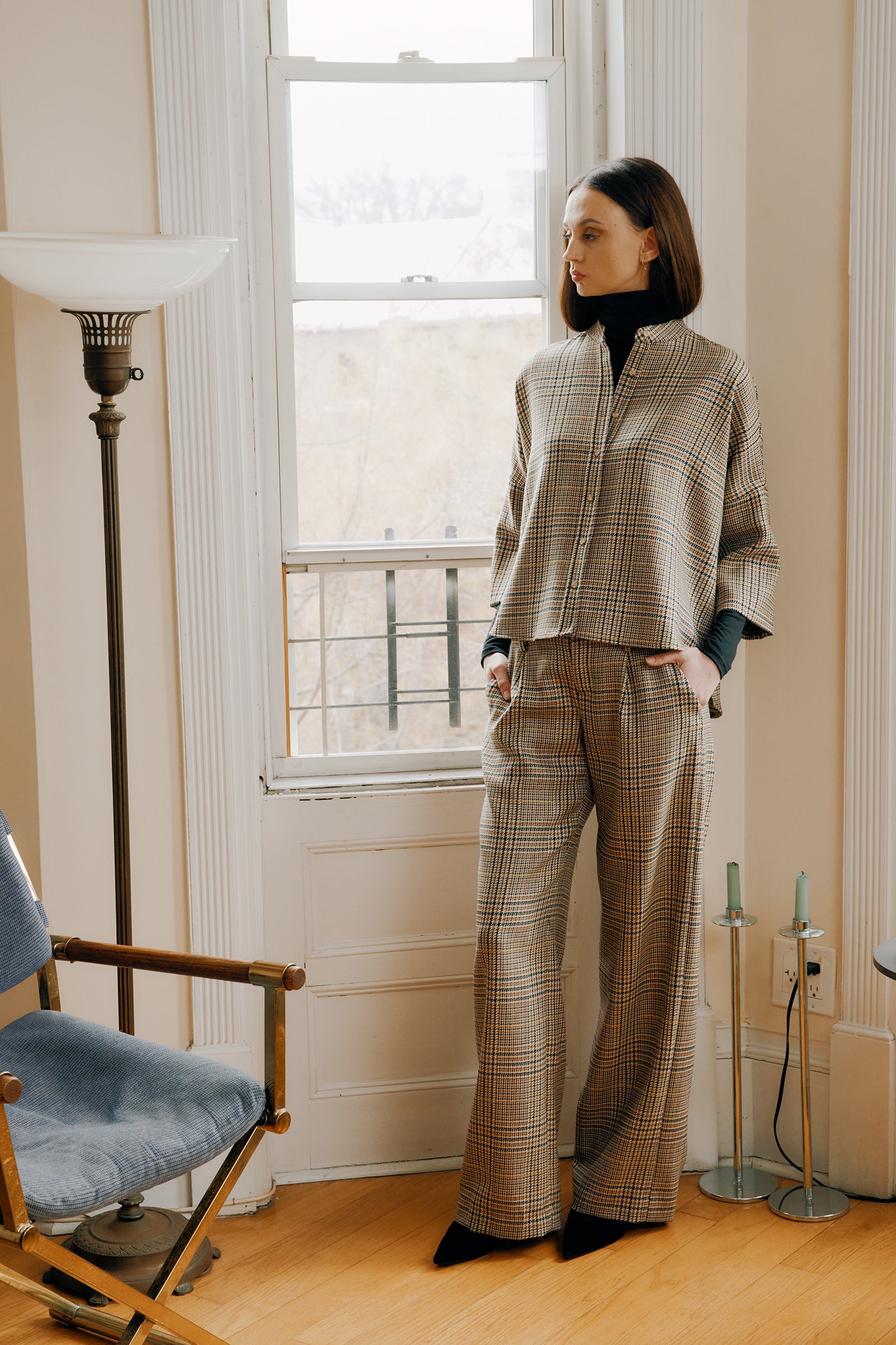 Kal Rieman Lilly Drop Shoulder Top in plaid on model standing by window hands in pocket