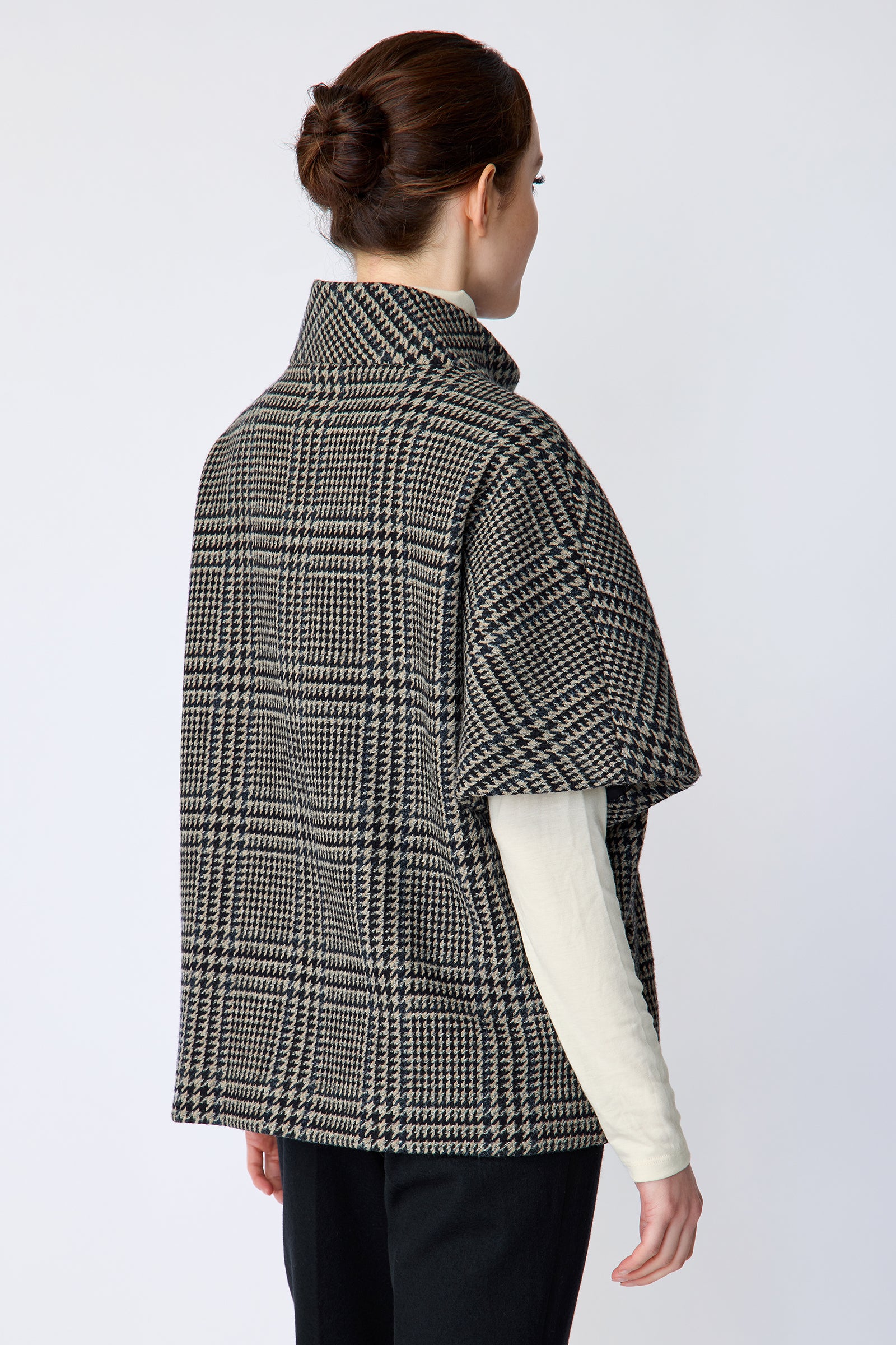 Woman wearing the Kal Rieman London Zip Vest in Multi Plaid and black pants, arms on the side, back view