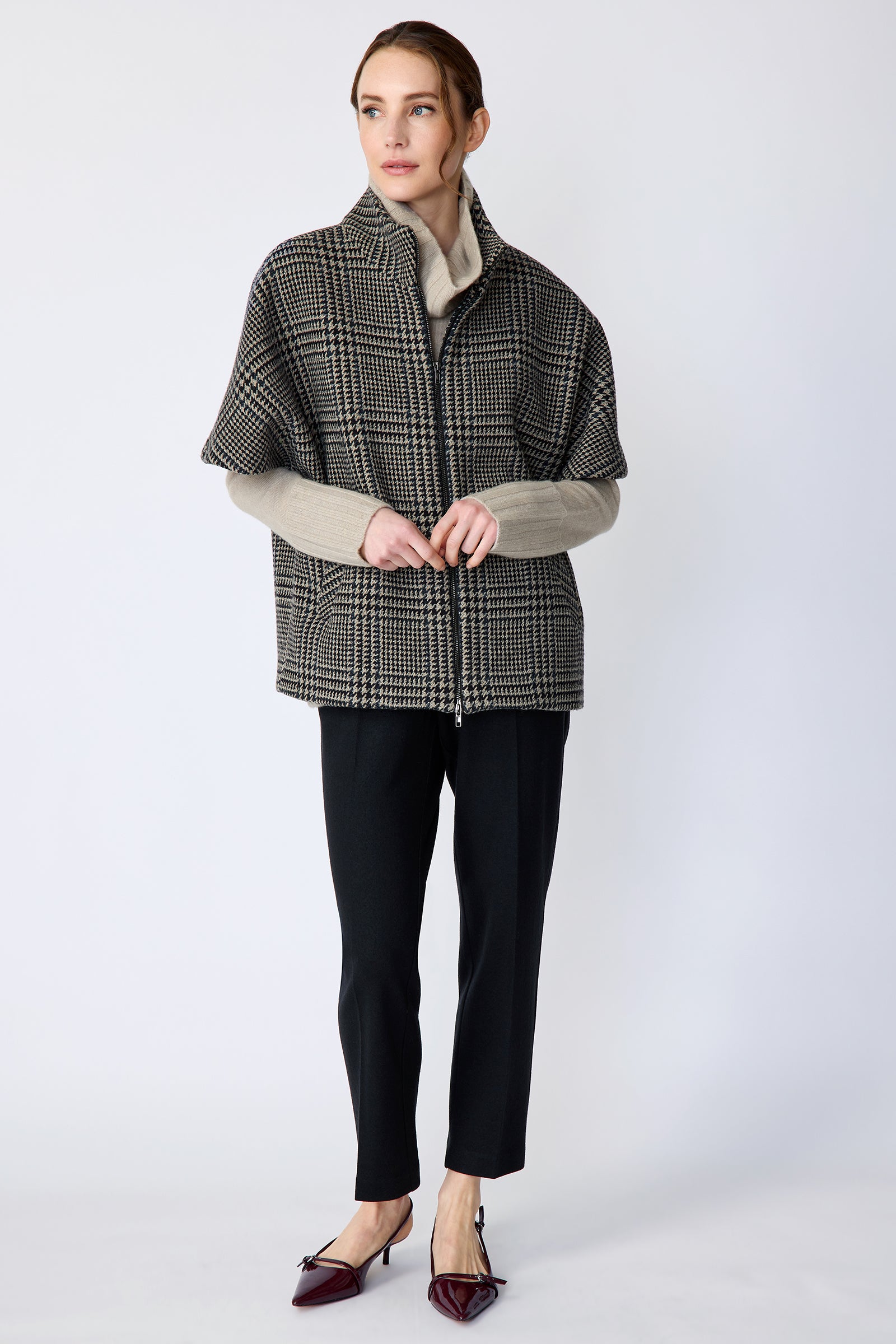 Woman wearing the Kal Rieman London Zip Vest in Multi Plaid and black pants, hands held in front, walking, looking sideways