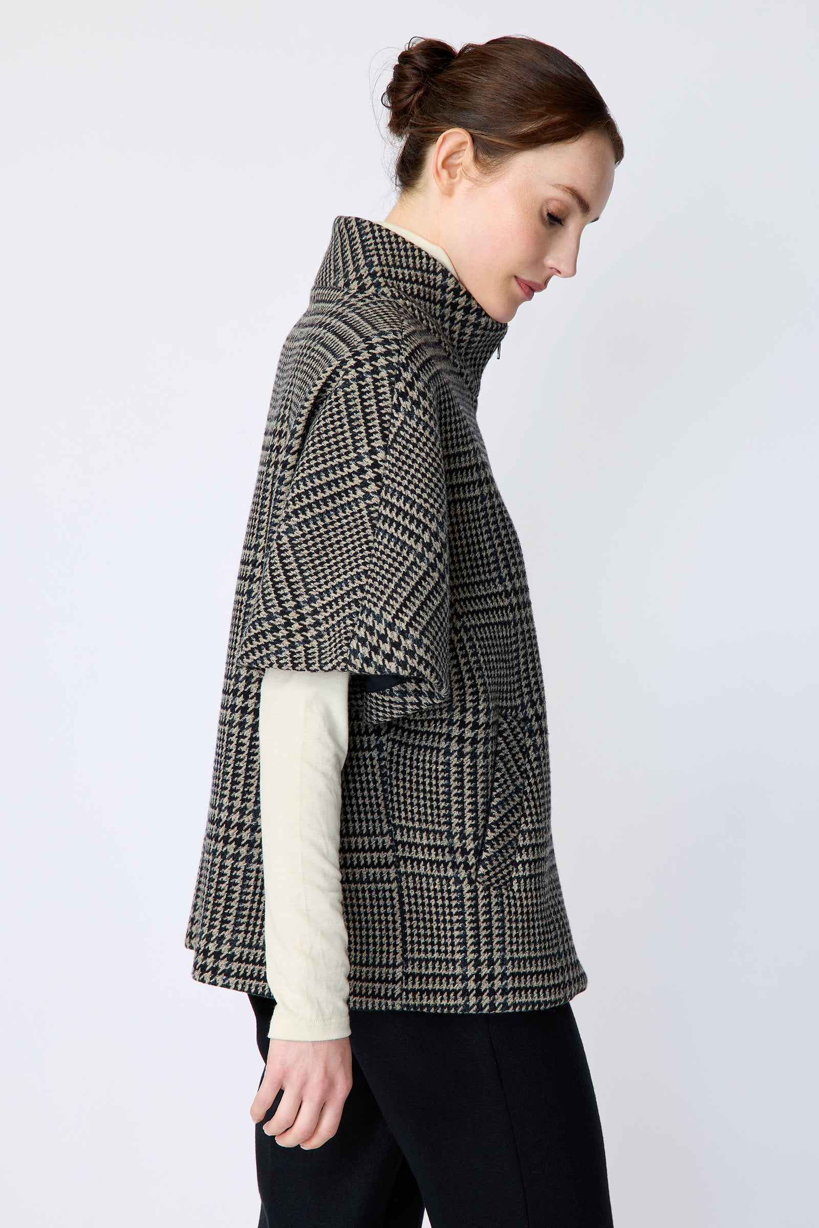 Woman wearing the Kal Rieman London Zip Vest in Multi Plaid and black pants, arms on the side, side view, looking down