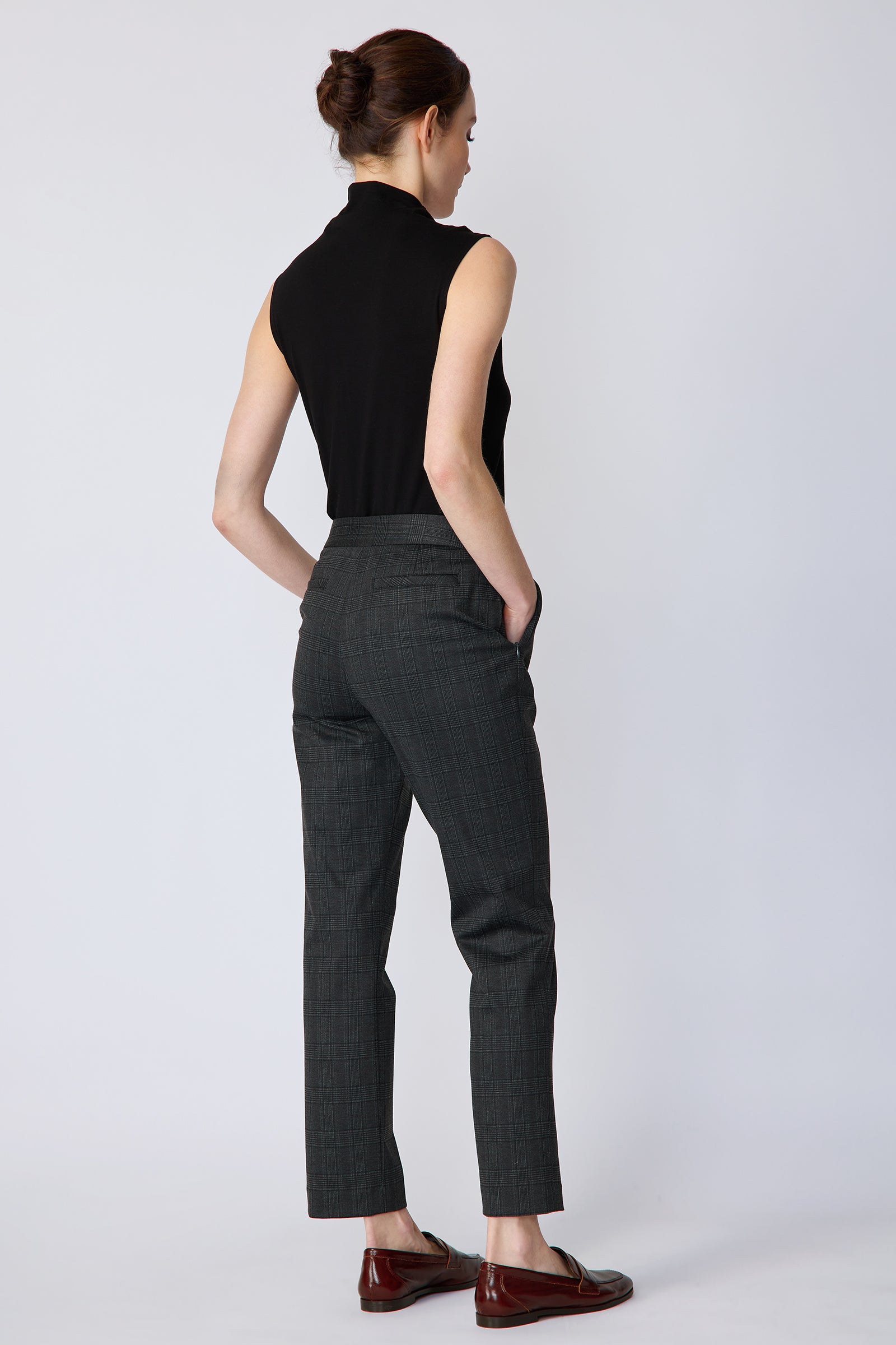 Woman wearing Kal Rieman Madison Pant in Black Glen Plaid and a black tank, hand in pant pocket, arm on the side on white background
