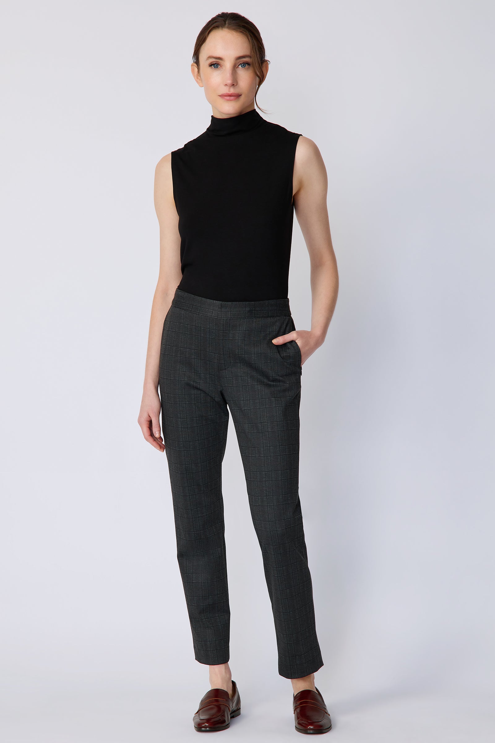 Woman wearing Kal Rieman Madison Pant in Black Glen Plaid and a black tank, hand in pant pocket, arm on the side on white background