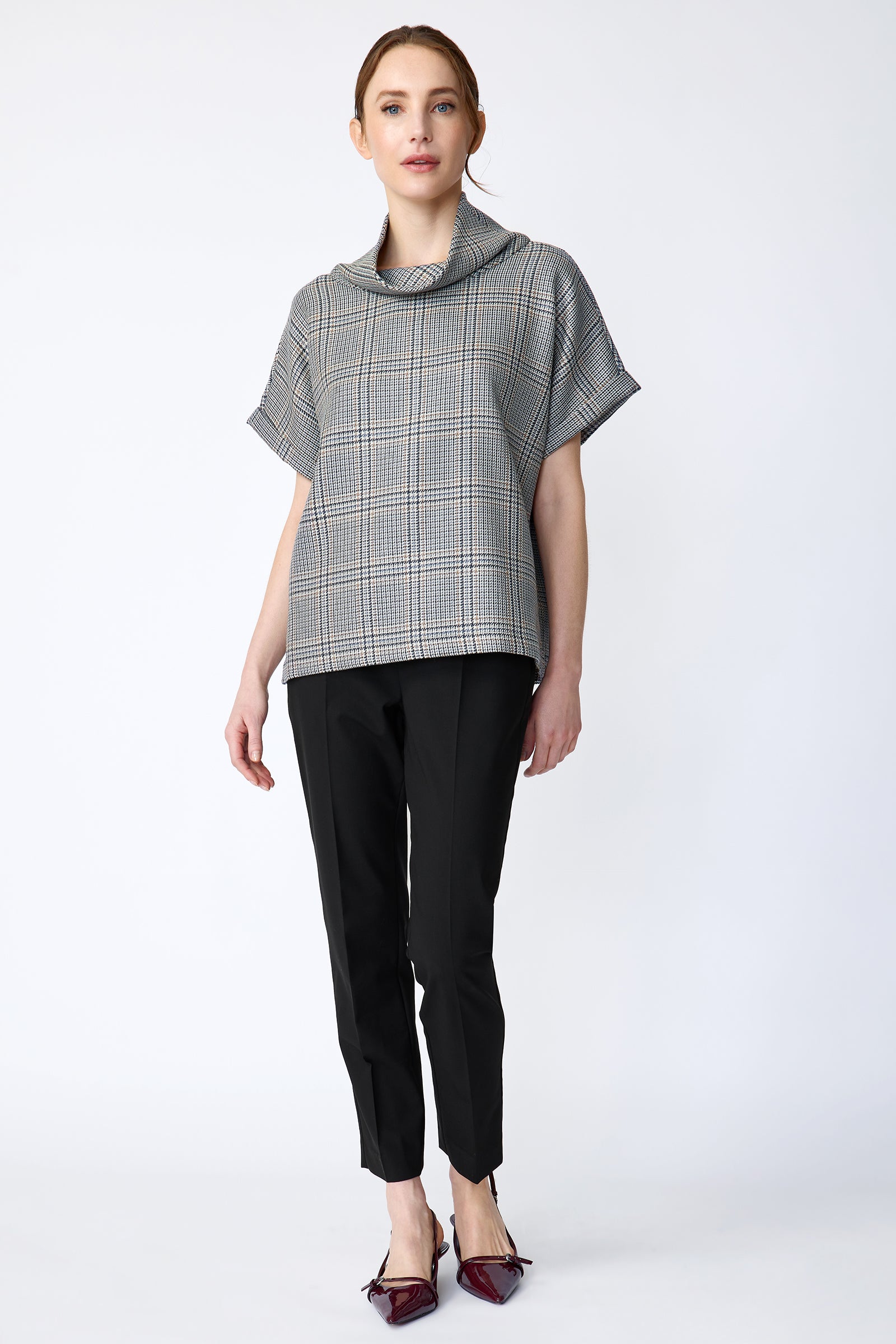 Woman wearing Kal Rieman Marin Top in Glen Plaid and black pants on a white background, arms on side